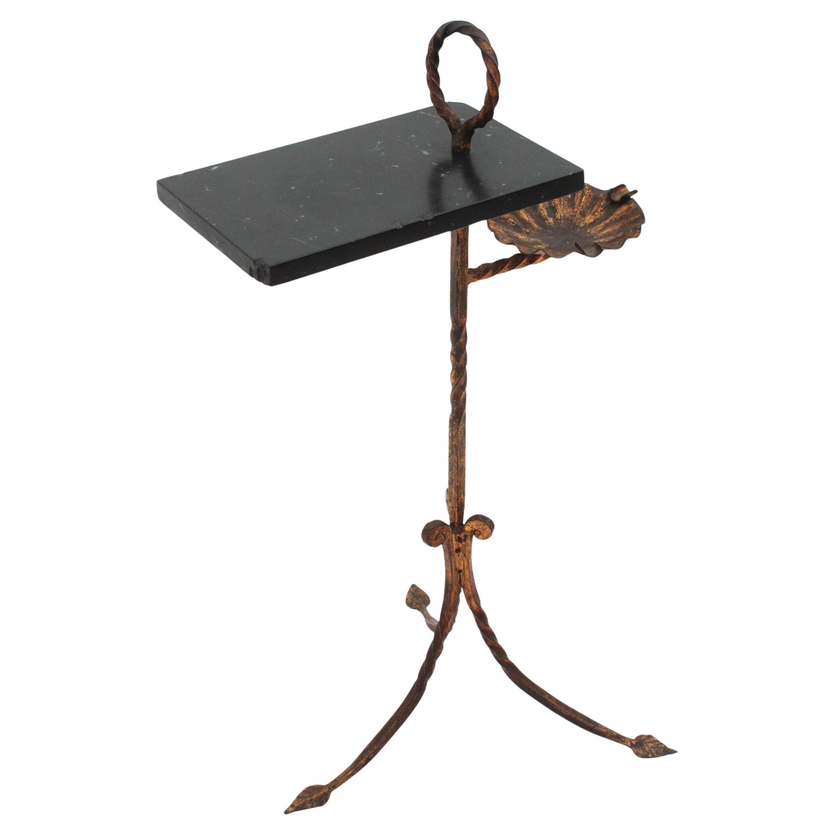 Table d'appoint unique en son genre en fer doré et marbre avec cendrier en émail coloré. Espagne, années 1940-1950.
Cette élégante table en fer forgé à la main présente un plateau en marbre gris et blanc reposant sur une structure en fer forgé avec