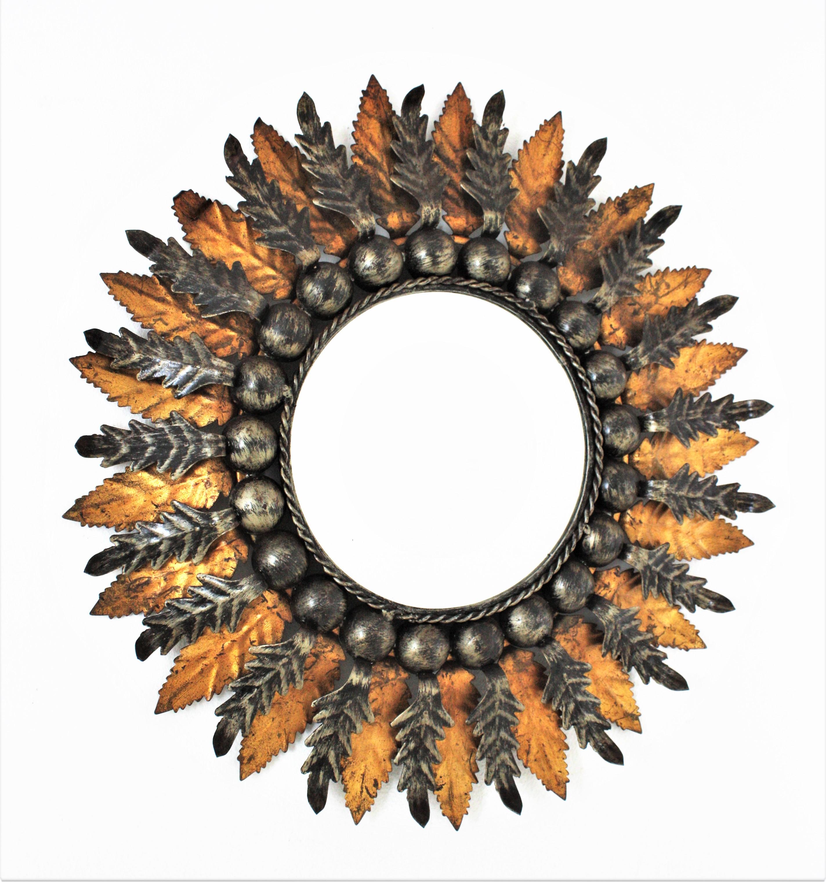 Double layered Foliage Two tone sunburst mirror, patinated metal, gilt metal, Spain, 1960s.
One of a kind gilt and silvered sunburst mirror with ball accents. This eye-catching sunburst mirror features a double layered leafed frame. A layer of gold
