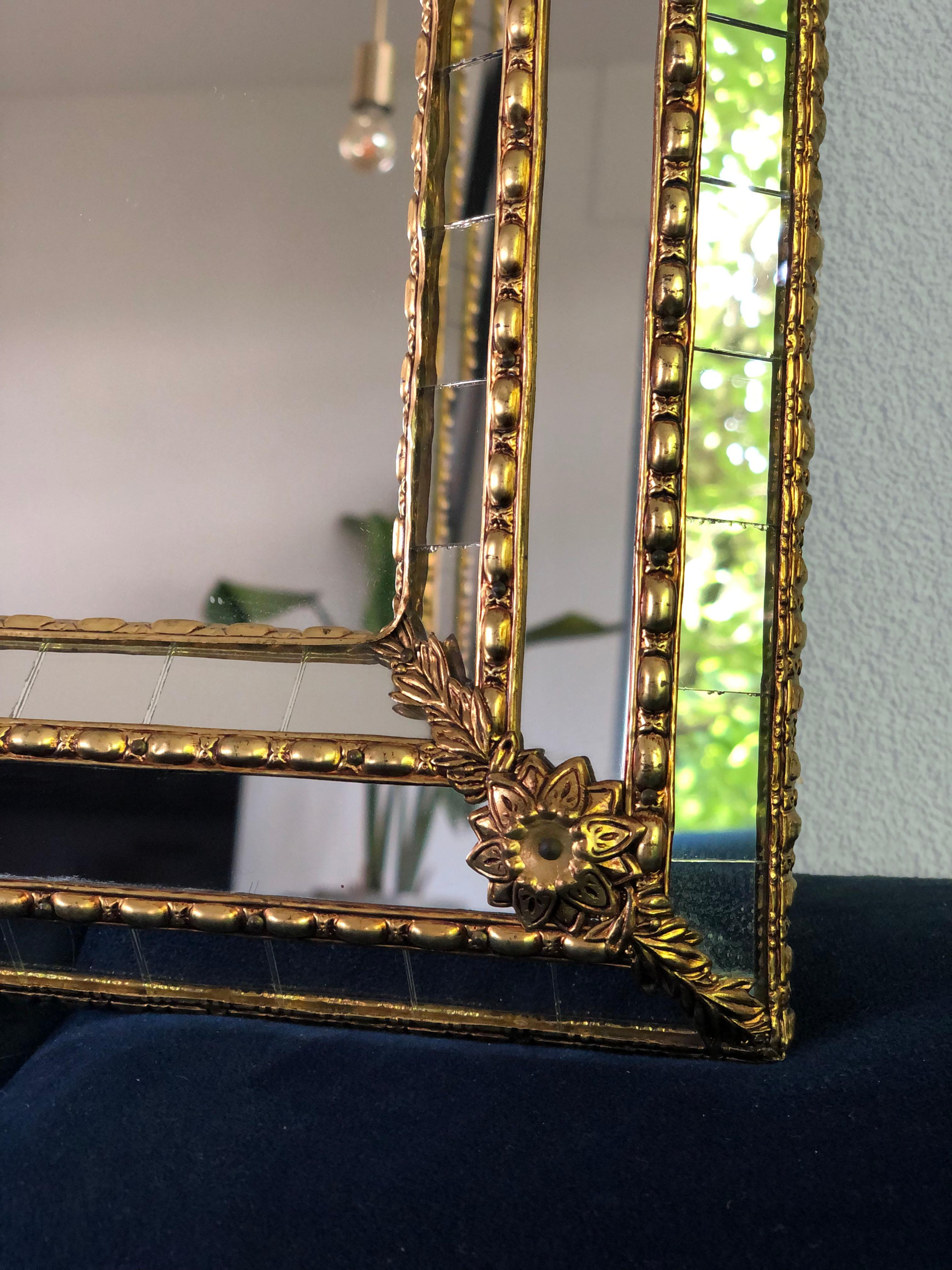 Beautiful handmade Venetian wide full length mirror from Spain 1980s. The frame has cut glass panes across the entire width, which is held together by a brass strip. The flawless trapezoidal mirror has a brass flower at each corner.

Object: