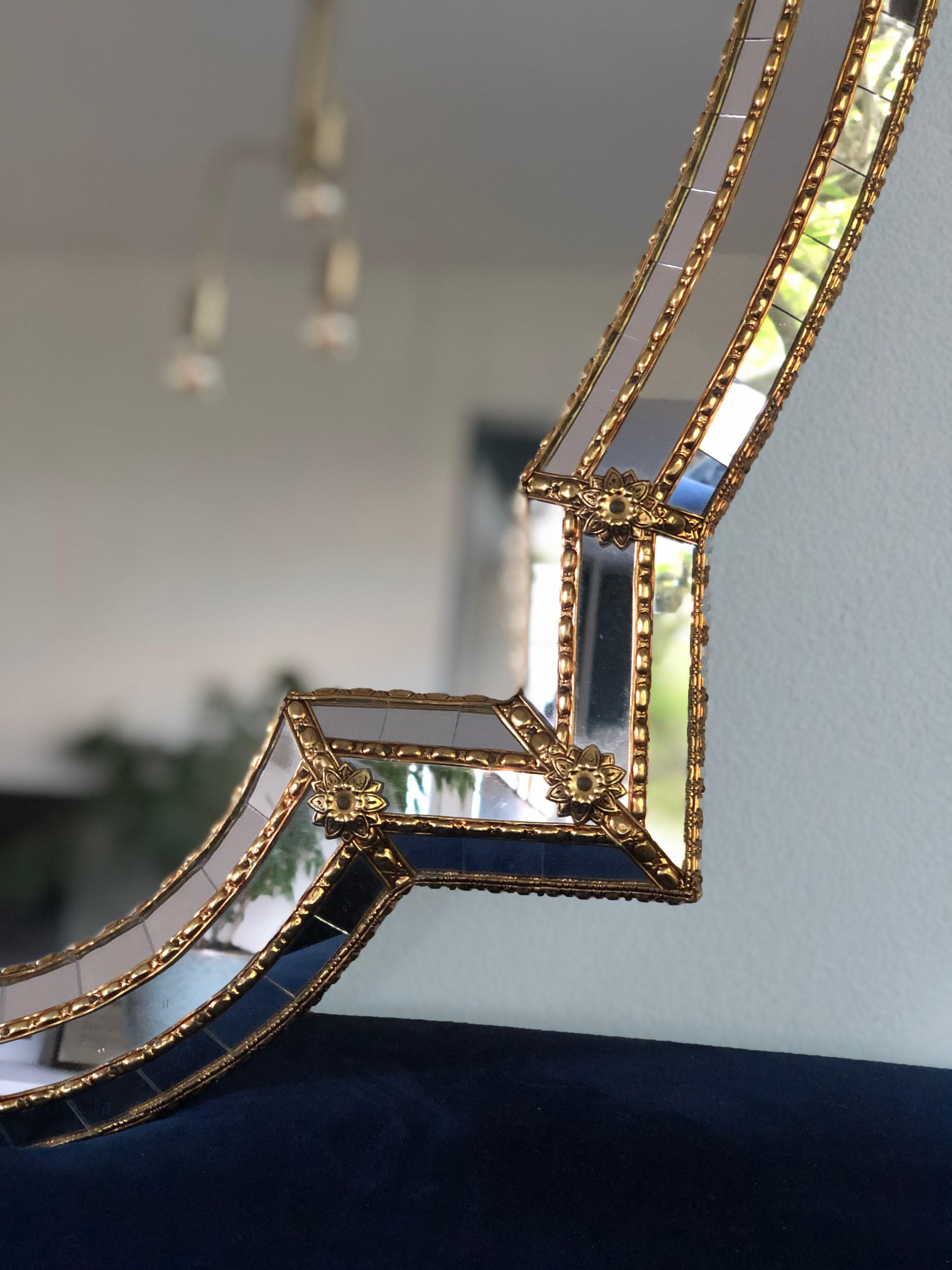 Beautiful handmade Venetian wide full length mirror from Spain 1980s. The frame has cut glass panes across the entire width, which is held together by a brass strip. The flawless trapezoidal mirror has a brass flower at each corner. The special