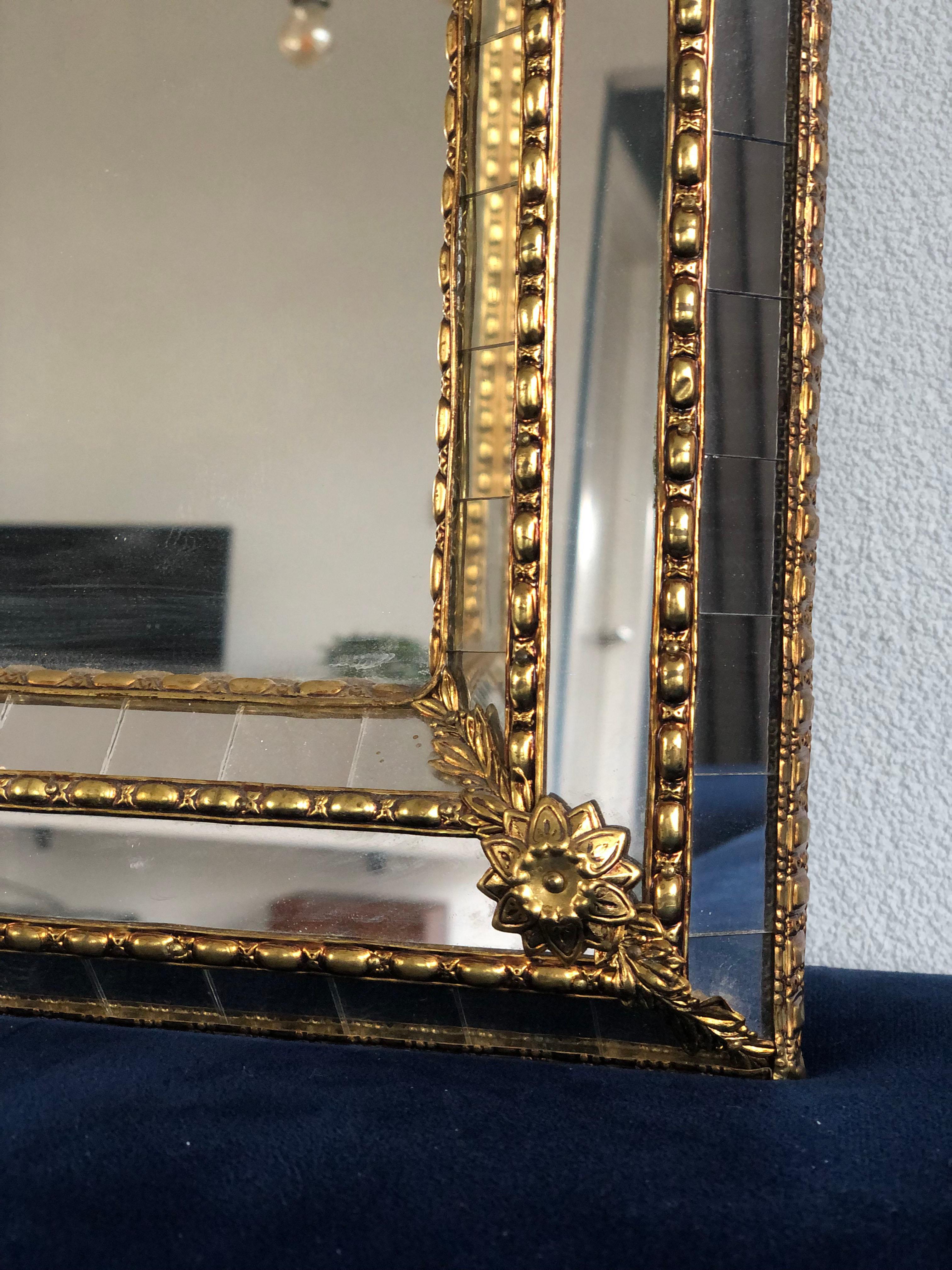 Beautiful handmade Venetian wide full length mirror from Spain 1990s. The frame has cut glass panes across the entire width, which is held together by a brass strip. The flawless mosaic trapezoidal mirror has a brass flower at each corner. 

Object: