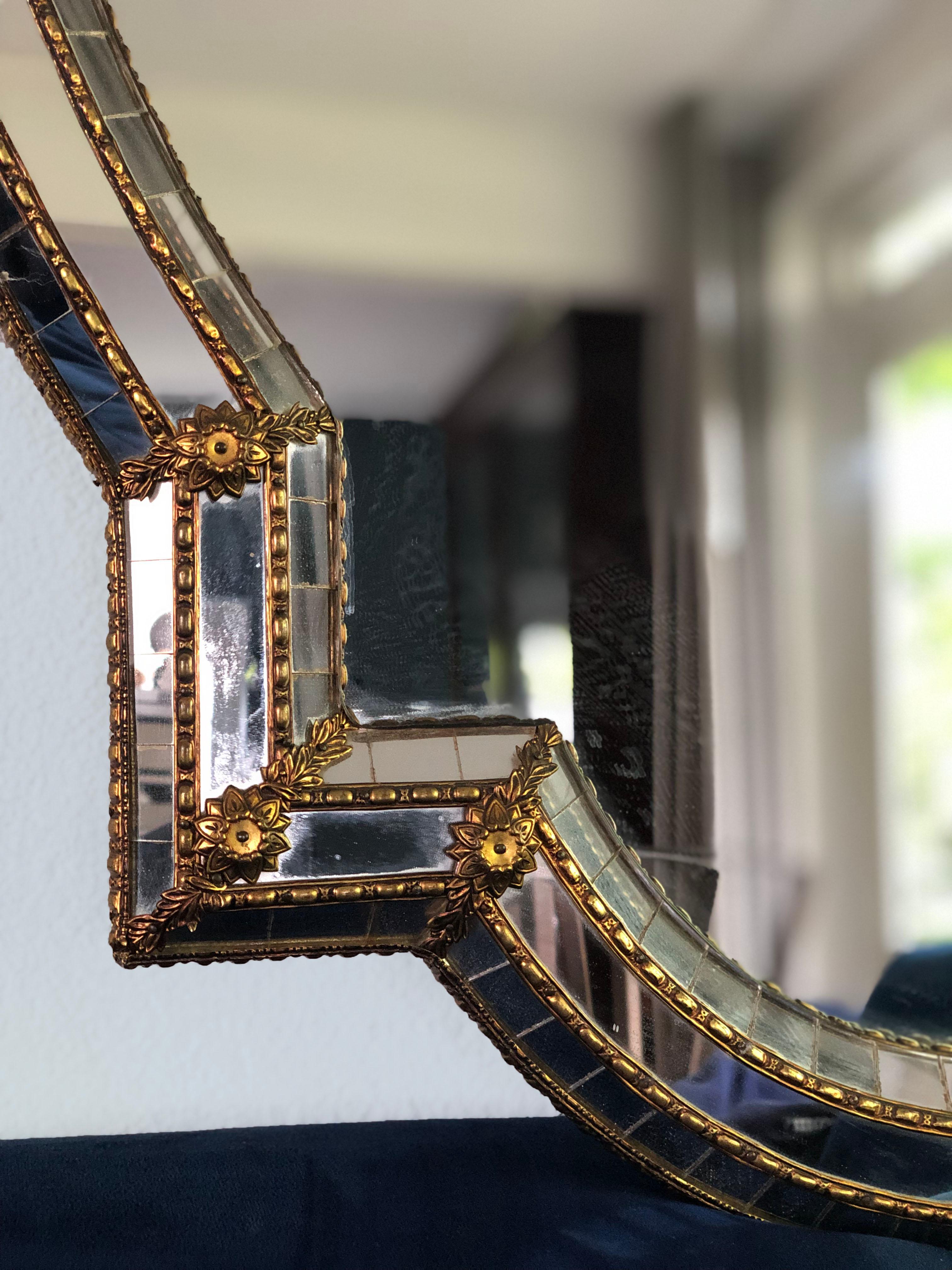 Beautiful handmade Venetian large mirror from Spain 1990s. The frame has cut glass panes across the entire width, which is held together by a brass strip. The trapezoidal mirror has a brass flower at each corner. The special shapes make the mirror