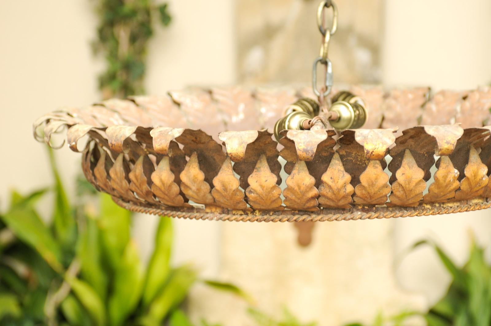 A vintage Spanish semi-flush gilt metal crown light fixture from the mid-20th century with frosted glass. This Spanish light fixture features a circular shape, adorned with two rows of foliage. The outer section is accented with leaves that are