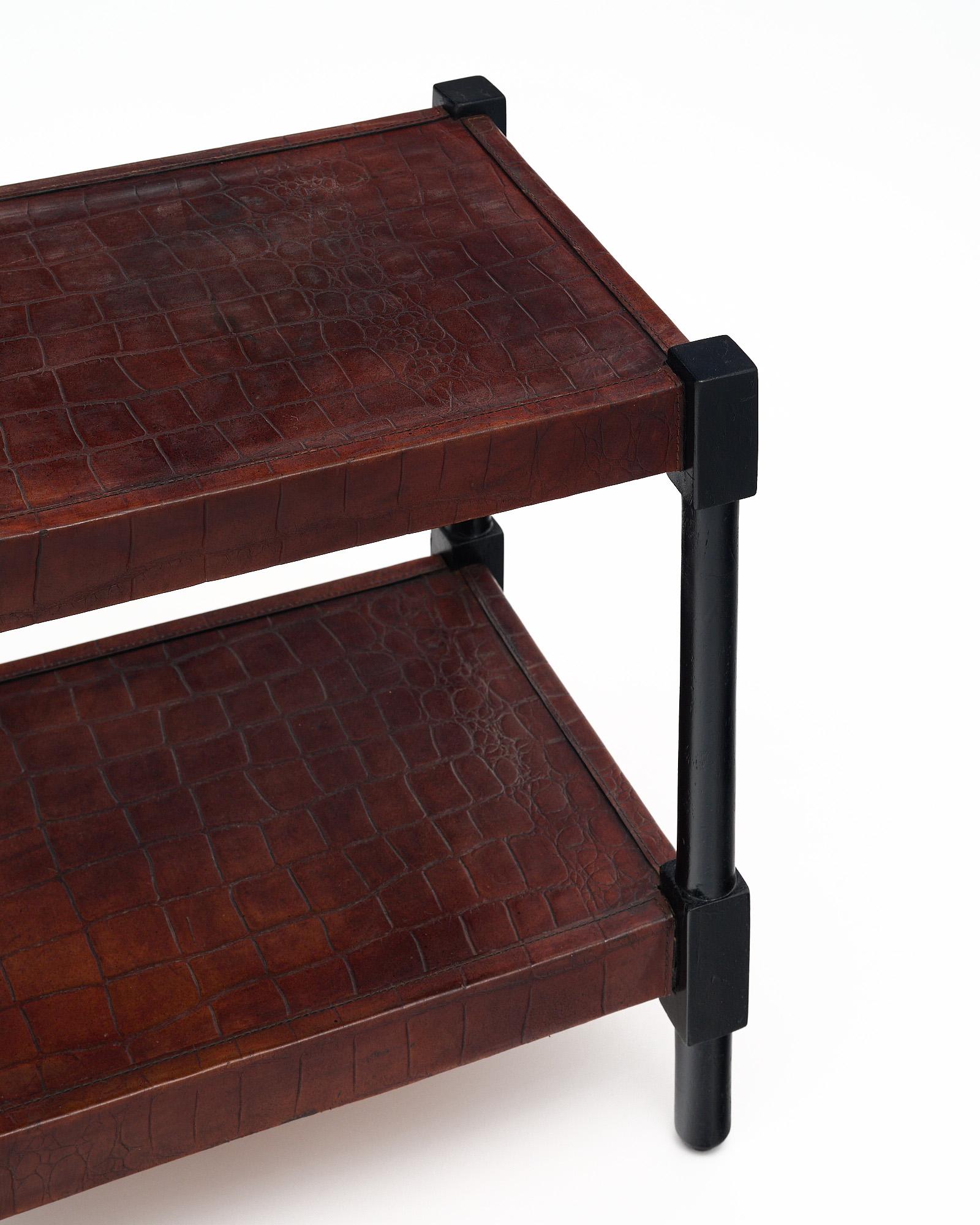 Vintage side table from Spain made with a wood structure and covered in a brown leather veneer with a snakeskin texture. This piece has ebonized legs and a lower shelf for functionality. It is by Spanish designer Valenti.