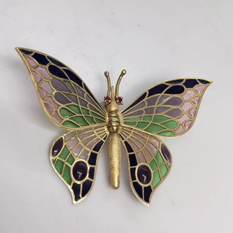 Verleihen Sie Ihrer Sammlung einen Hauch von Vintage-Eleganz mit dieser exquisiten Schmetterlingsbrosche aus Spanien. Die aus 18-karätigem Gelbgold und Emaille gefertigte Brosche zeichnet sich durch ein atemberaubendes Plique-a-Jour-Design aus, das