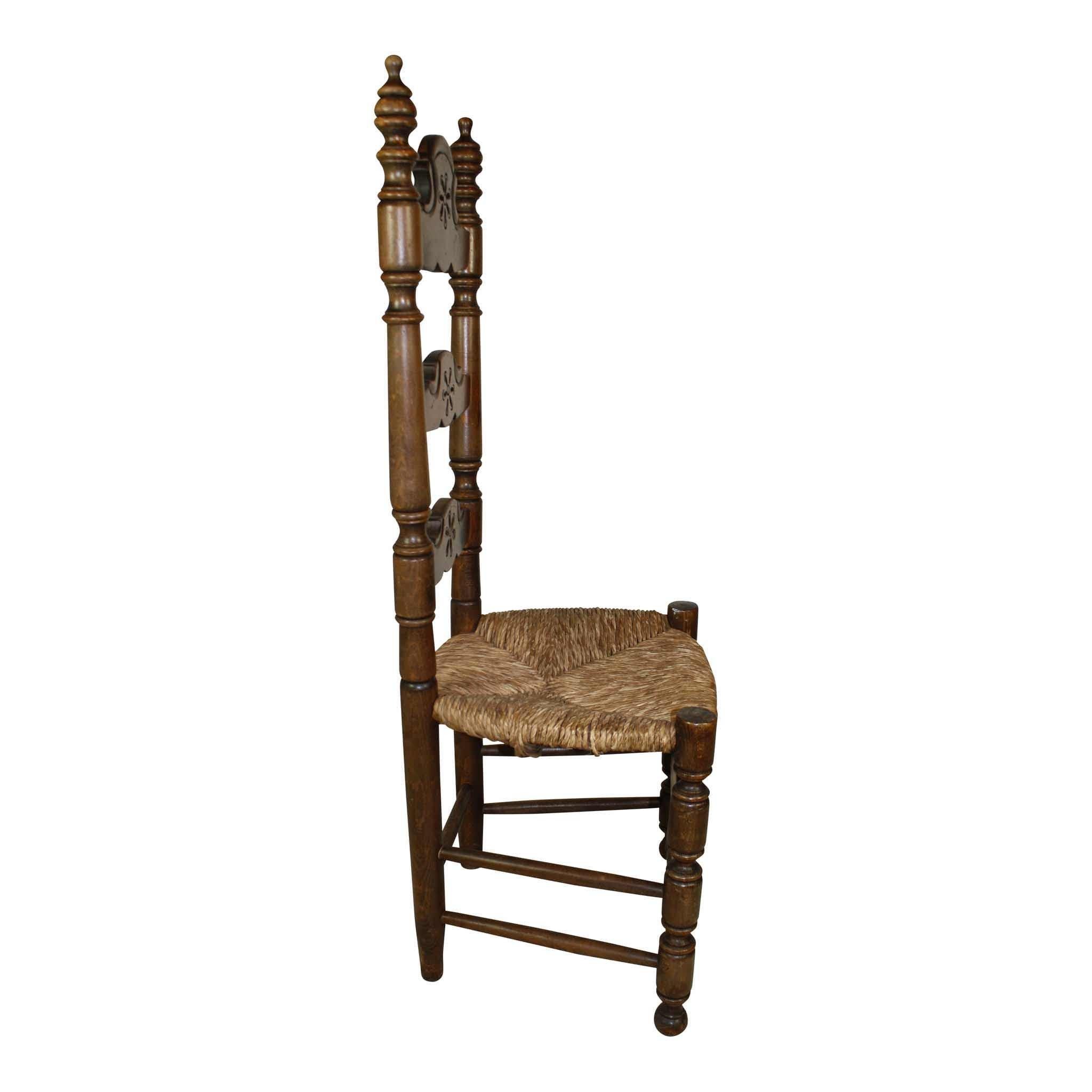 Originating in Spain, this set of four ladder back chairs features walnut frames and rush seats. Turned stiles are capped with finials and support shaped rails with single flowers carved at their centers. The turned front legs terminate in ball feet