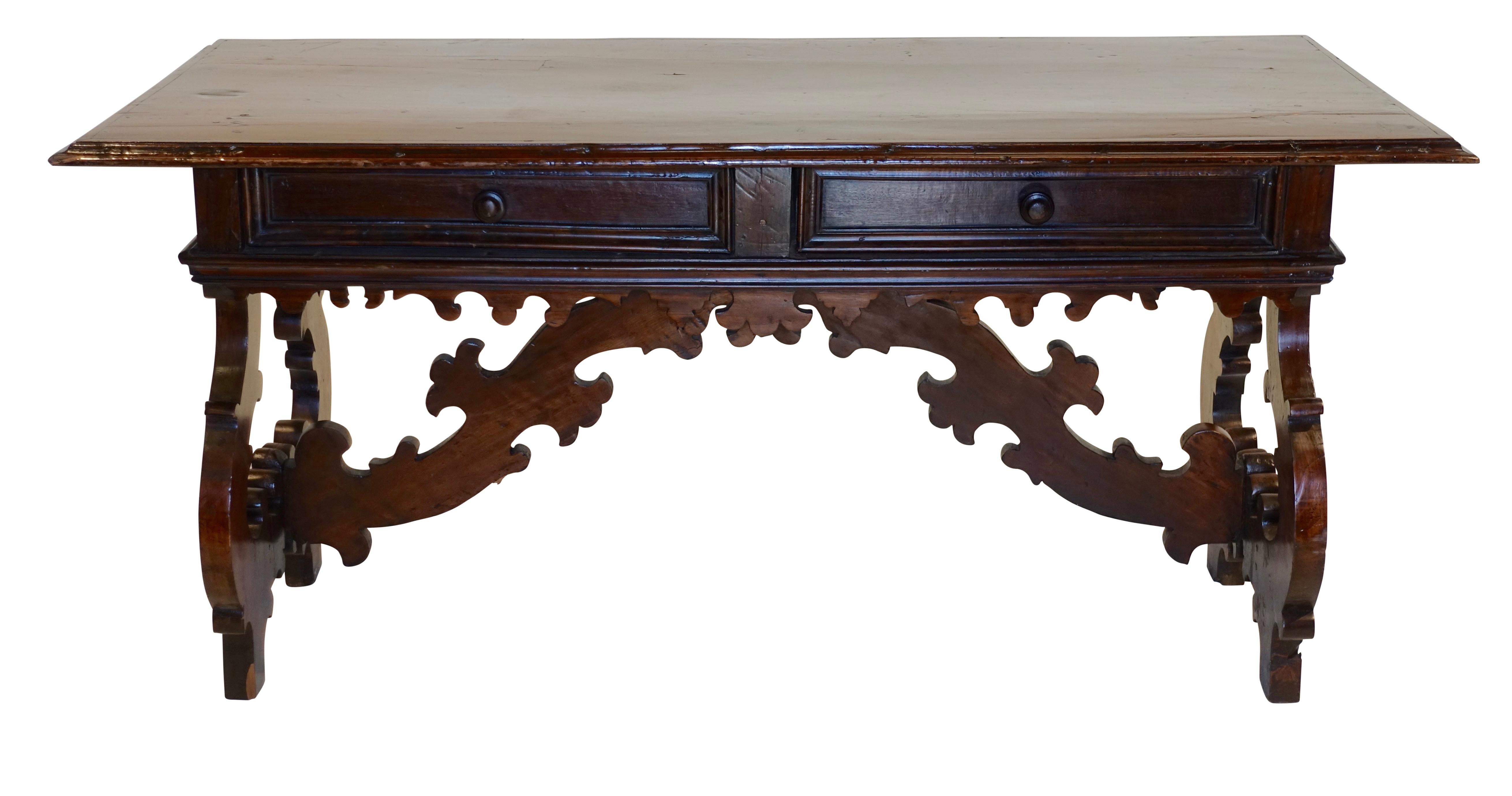 An exuberant library table or desk having a walnut molded edge around the top, two drawers, and fluidly carved legs and support braces. Spanish, 18th century.

 