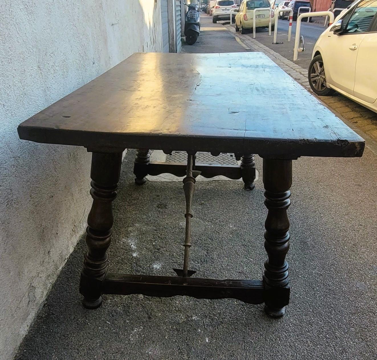 Großer Tisch aus spanischem Nussbaumholz, 17. Jahrhundert, mit schmiedeeisernen Querstreben.   

Die Platte besteht aus einem einzigen Brett und wird mit Schrauben befestigt.   

Tisch aus dem 17. Jahrhundert, wie er ist: einige Risse, Spuren von
