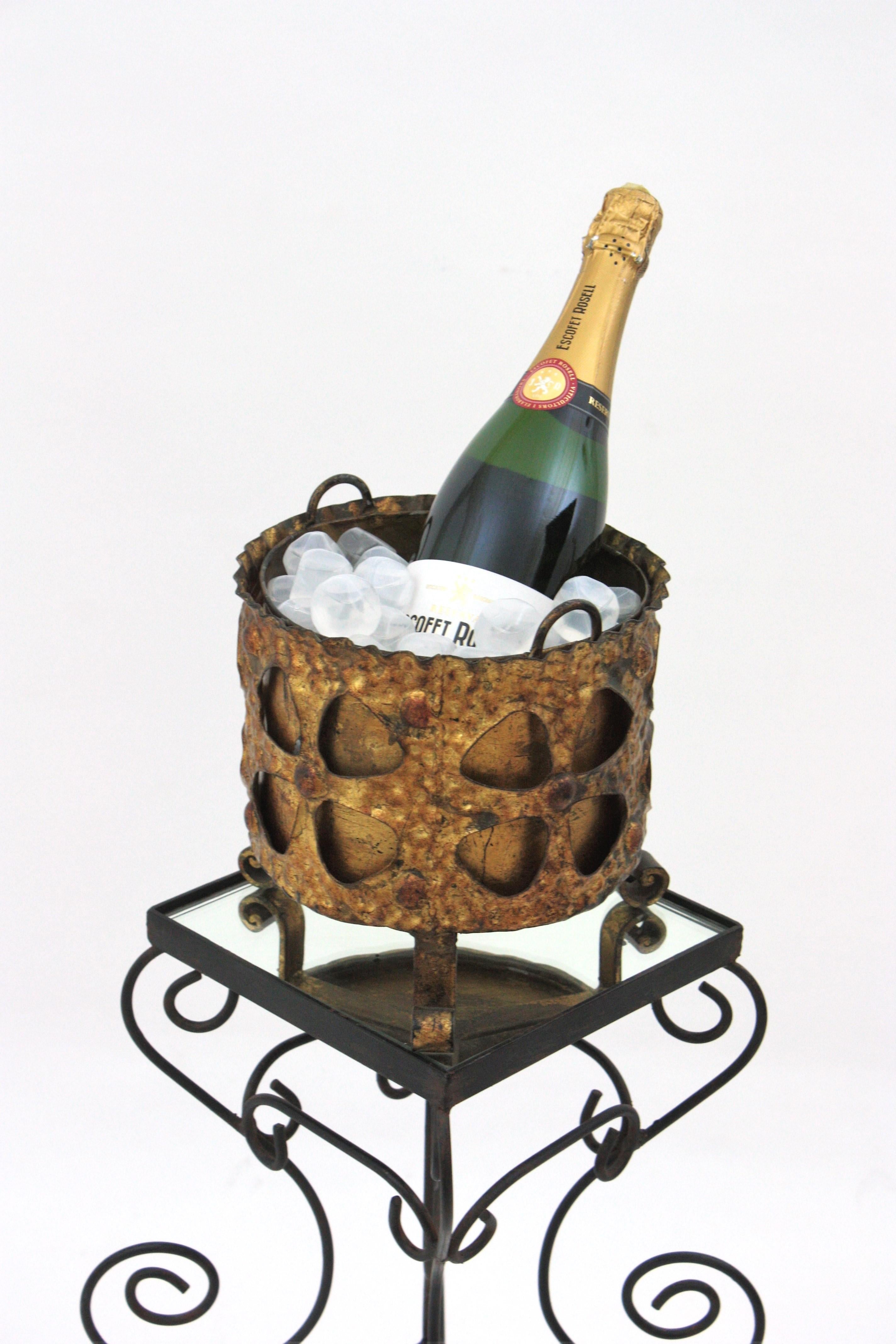 Secchiello per vino champagne con motivi floreali, foglia d'oro, ferro dorato. Spagna, anni '40-'50.
Raro da trovare.
Un bellissimo secchiello per il ghiaccio in ferro battuto a mano con finitura in foglia d'oro. Si regge su tre piedini a voluta e