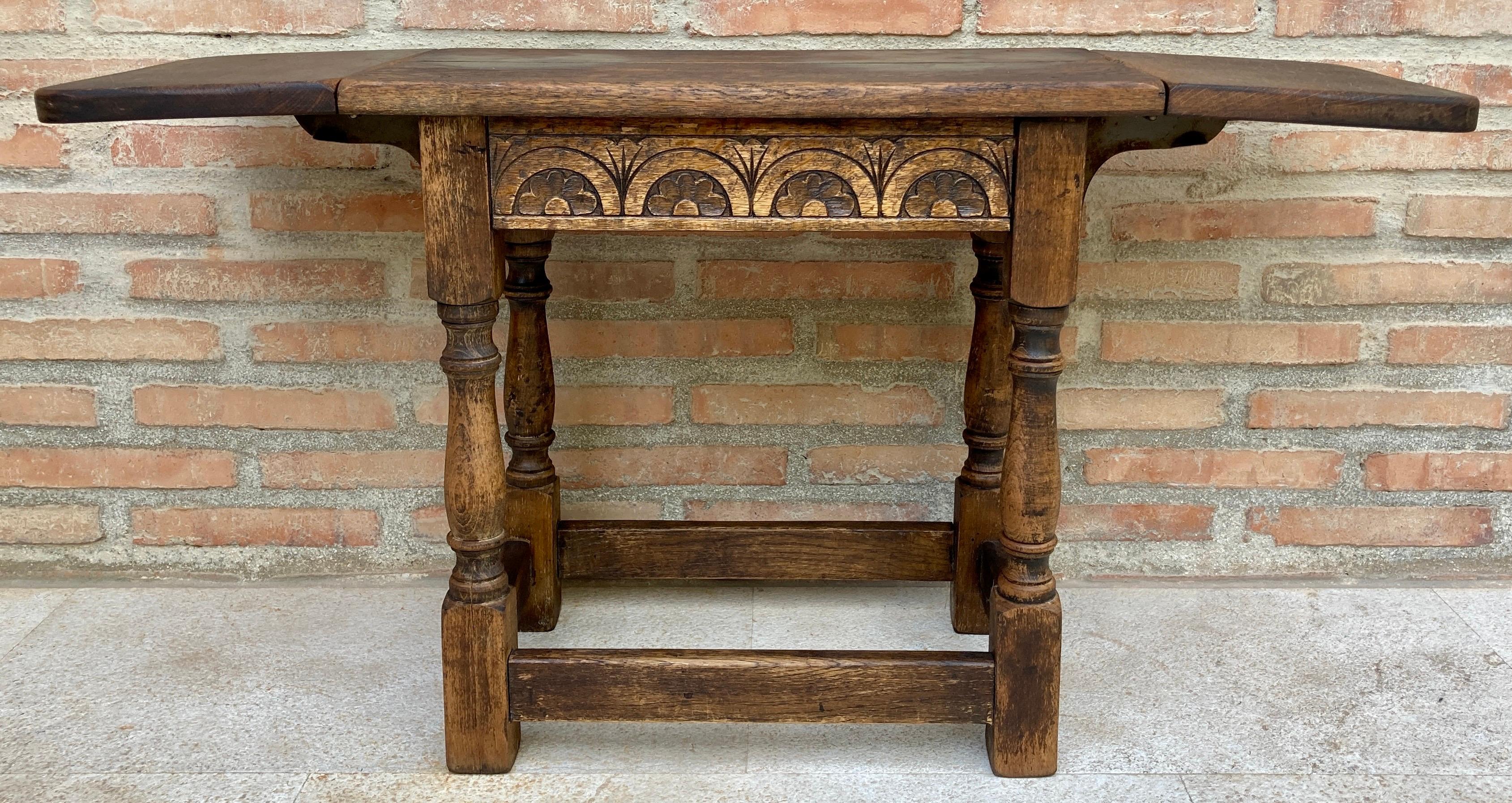 Side table with wings in walnut wood in the Spanish Castilian style. 
Beautiful small side table with side wings. 
A very fine quality early 20th century baby walnut table which has 
its well-preserved lid with a flap on each side. Raised on