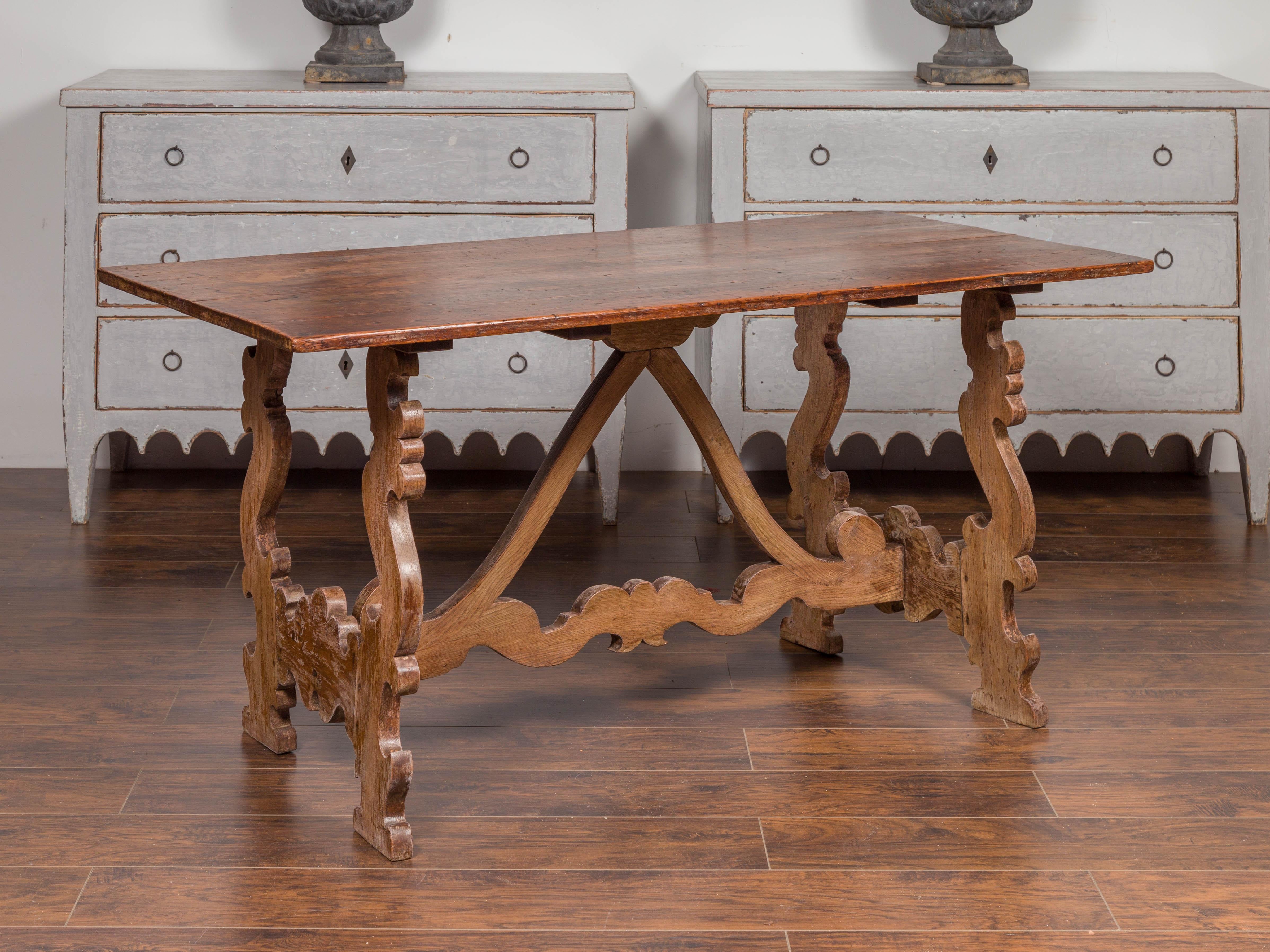 Cette table console espagnole Fratino du milieu du XIXe siècle présente un plateau rectangulaire avec une belle patine sur une base à tréteaux de style baroque. Deux pieds en forme de lyre sont reliés l'un à l'autre ainsi qu'au plateau de la table
