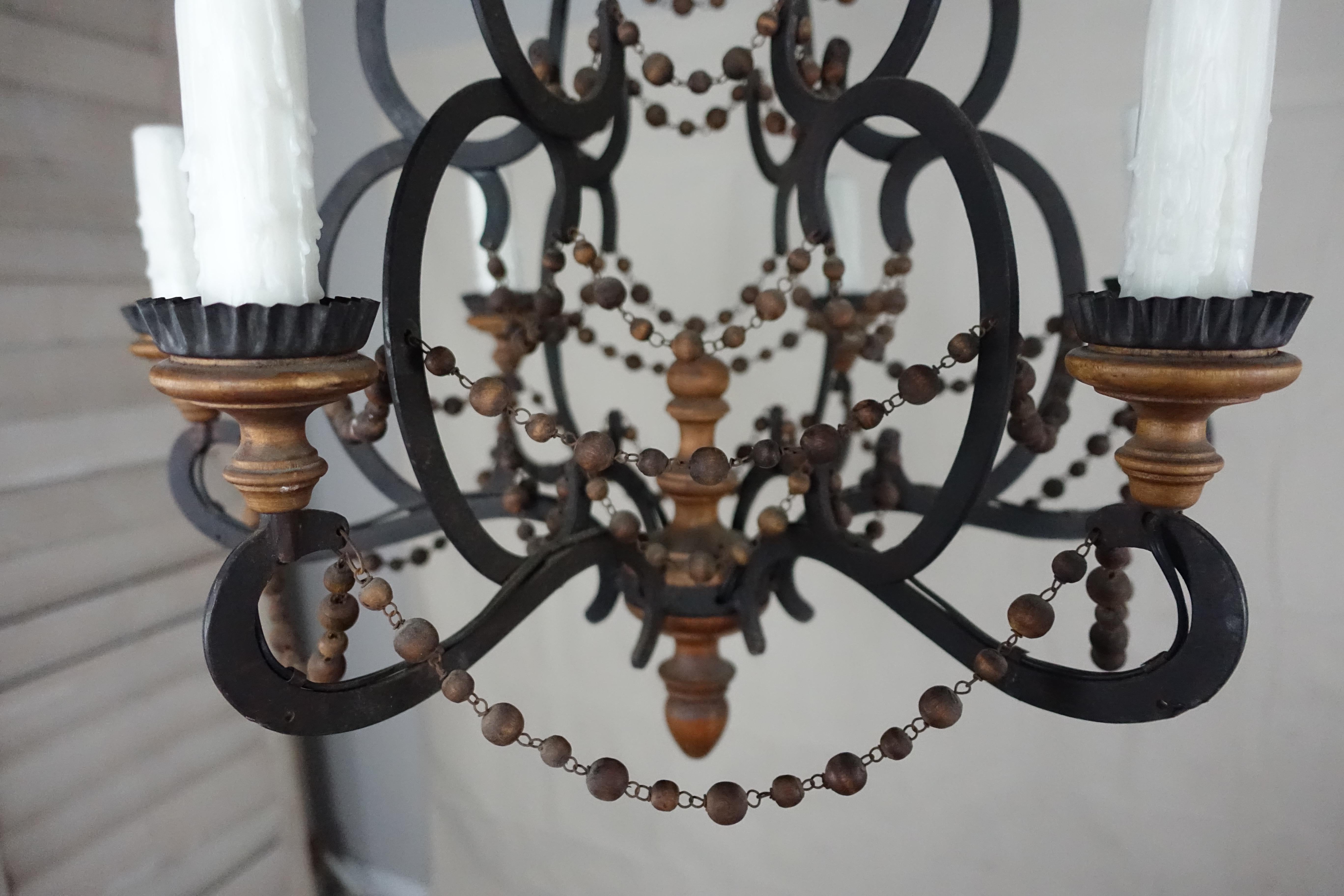 Spanish wrought iron and wood beaded chandelier with iron and wood frame. The 6-light fixture has garlands of natural colored wood beads throughout. Wood bobeches and centre finial. The fixture has been newly wired with drip wax candle covers and