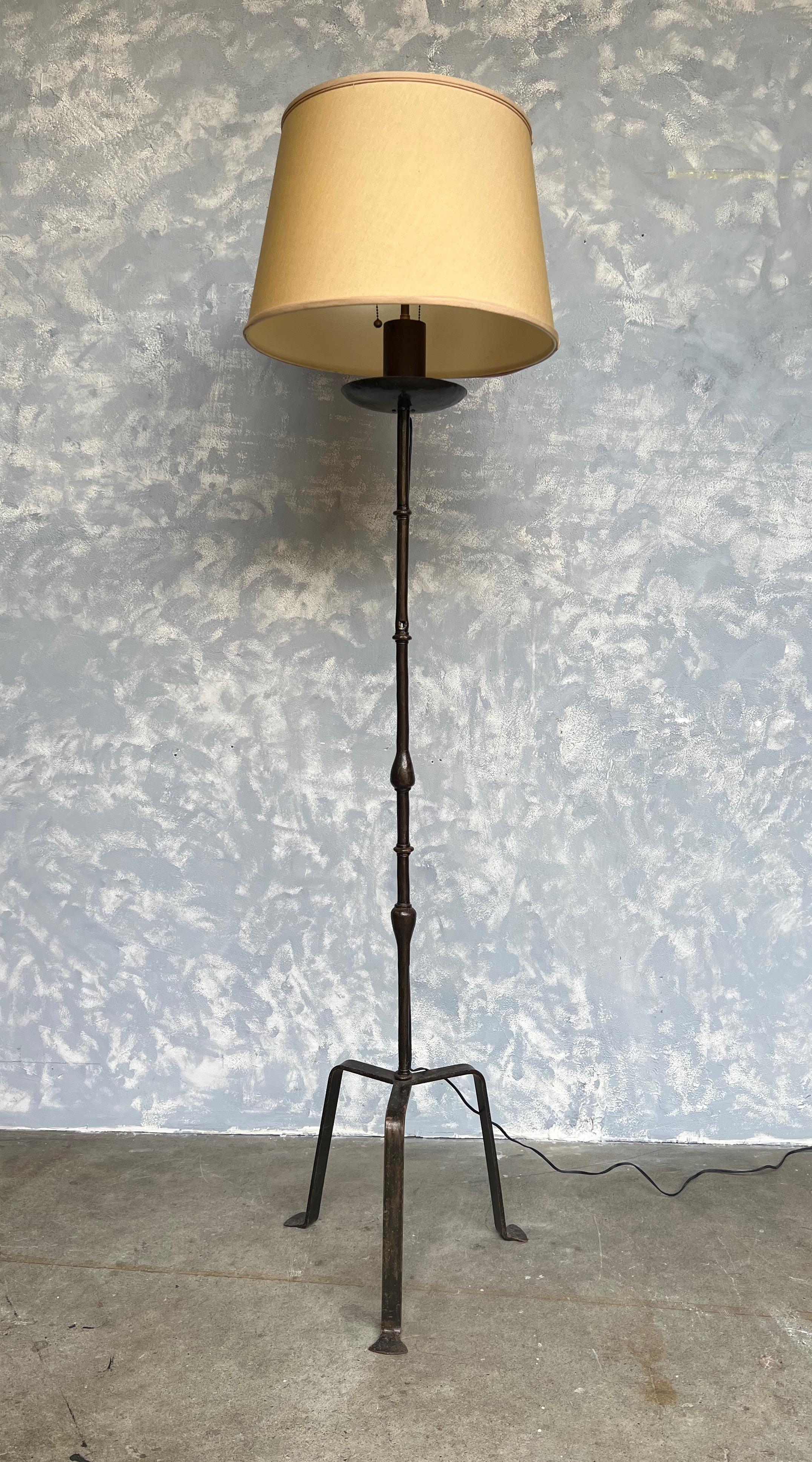This exceptional Spanish floor lamp from the 1950s stands on an elongated tripod base, showcasing its remarkable design. Constructed with solid iron, the lamp features a rich deep bronze patina with a clear lacquer coat to prevent tarnishing. The