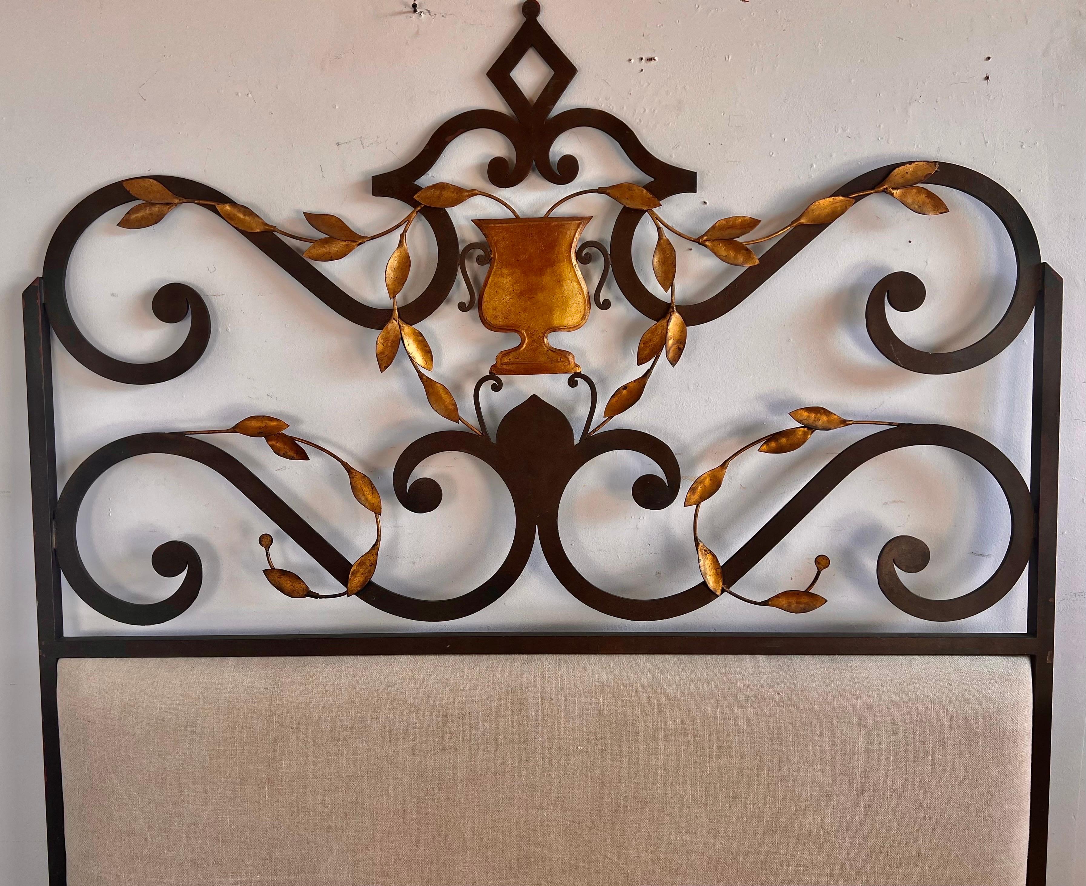 King size Spanish wrought iron headboard with a gold leaf urn & gold leaf leaves depicted in the center of the design. The headboard was newly upholstered with a washed Belgium linen in a natural oatmeal coloration.