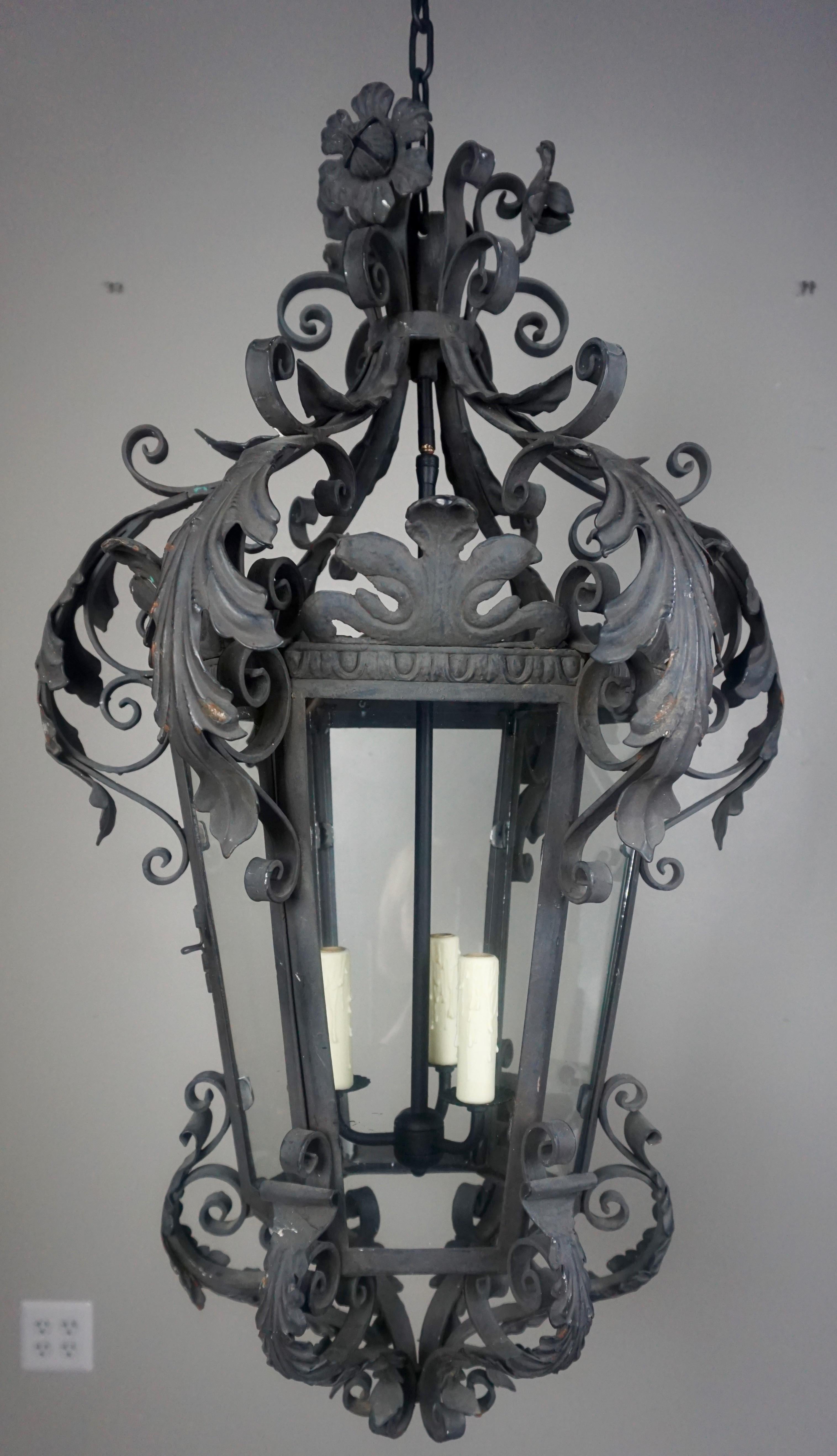 Spanish wrought iron 3-light Lantern with beautiful acanthus leaves and flowers throughout. Glass inserts. The lantern is newly rewired with wax candle covers. Includes chain & canopy, ready to install.