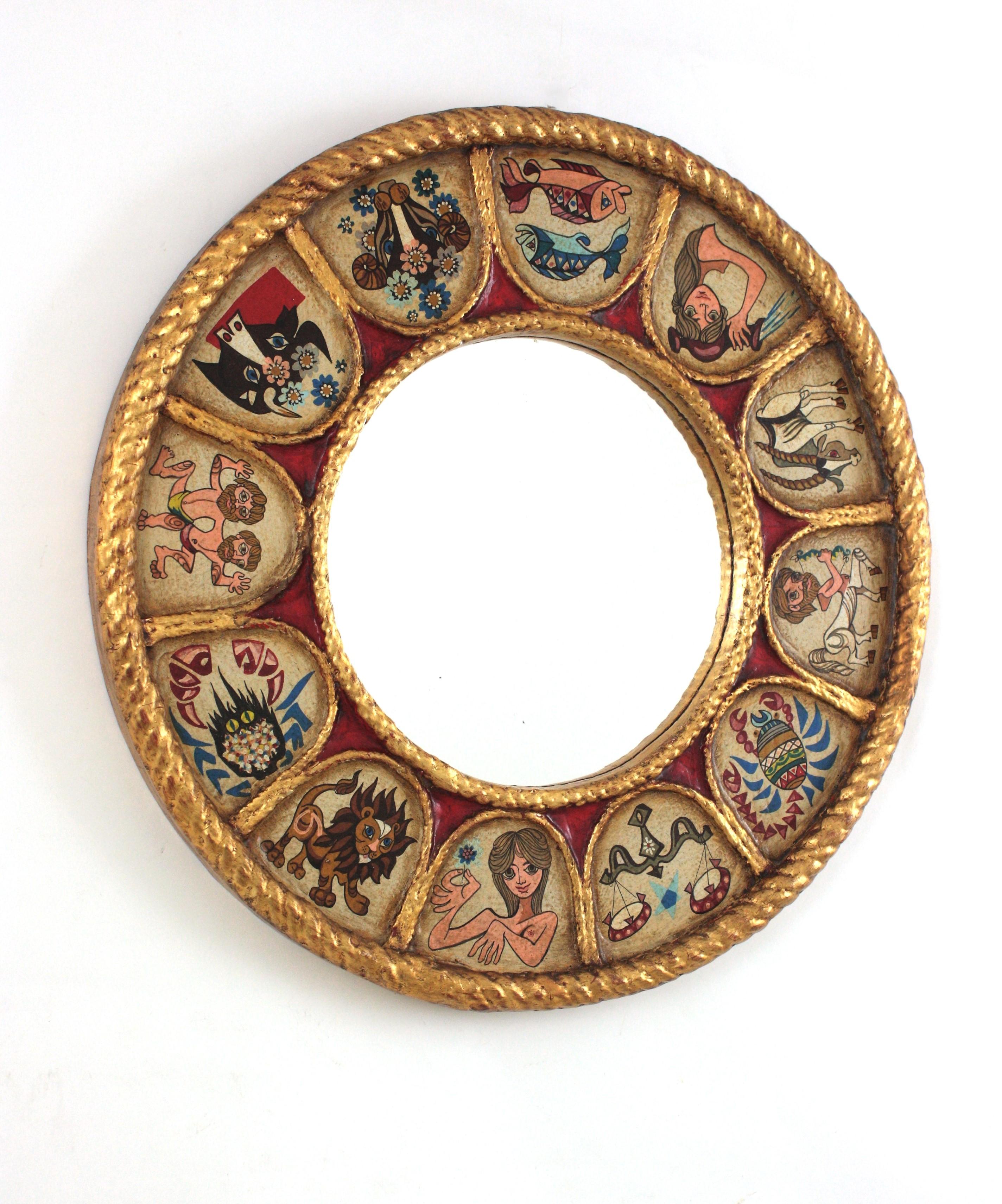 Zodiac round sunburst mirror in gilt polychrome wood, Spain, 1950s-1960s.
Handcrafted Horoscope mirror with giltwood round frame and hand painted polychromed 12 signs of zodiac arround the frame. 
Sunburst design surrounding the glass and Naif hand