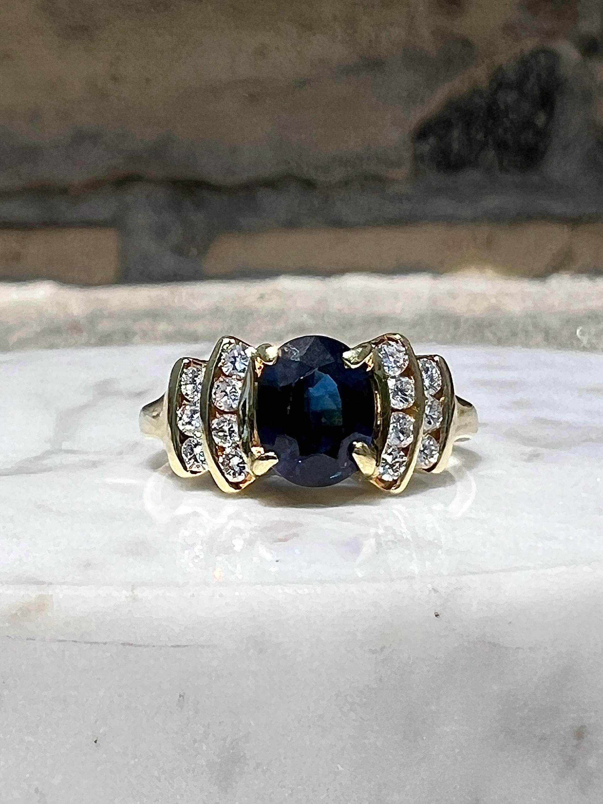 This elegant Spark Creations contemporary ring is expertly crafted in 18 karat yellow gold and showcases a vibrant oval-cut blue sapphire measuring approximately 7.36 x 5.87 mm and weighing an estimated 1.44 carats. The sapphire displays a rich,