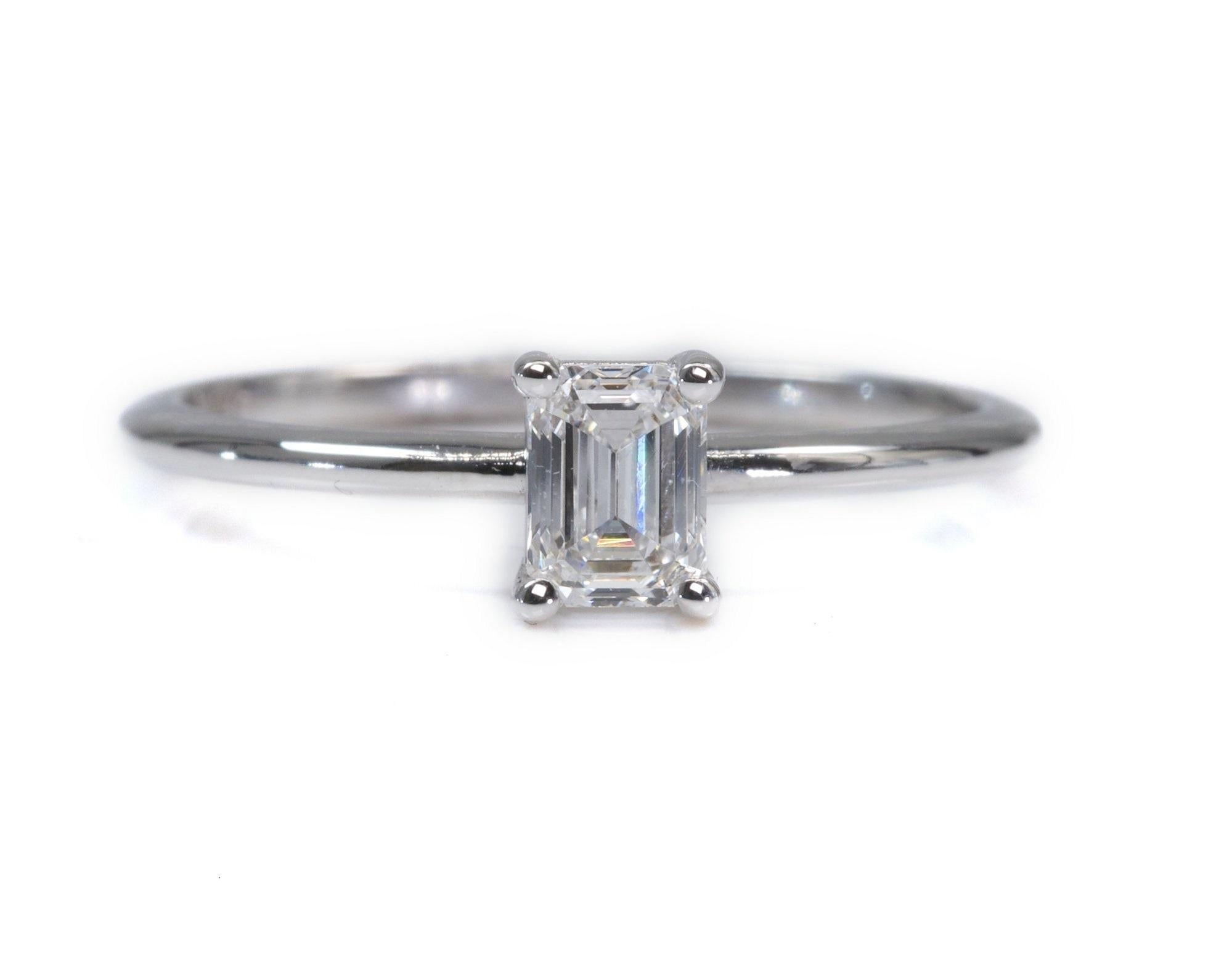 A beautiful classic engagement ring with a dazzling 0.86 carat emerald cut natural diamond. The setting is made of 18K white gold with a high quality polish. The main stone has a laser inscription and an IGI Certificate. It comes with a fancy