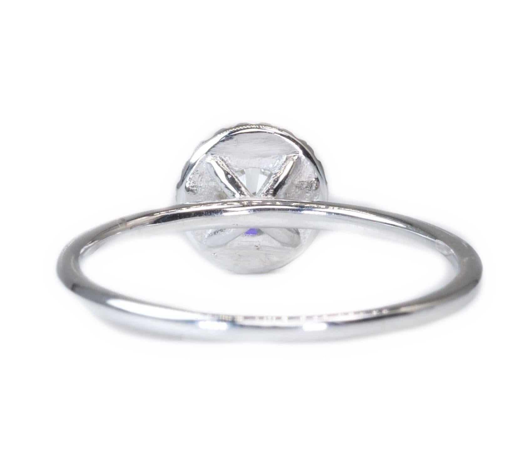 A luxurious and beautiful solitaire halo ring with a stunning round brilliant natural diamond as the main stone totaling 0.65 carats, and 0.35 carats of round brilliant diamonds as side stones. This ring is made from 18k white gold, has an IGI