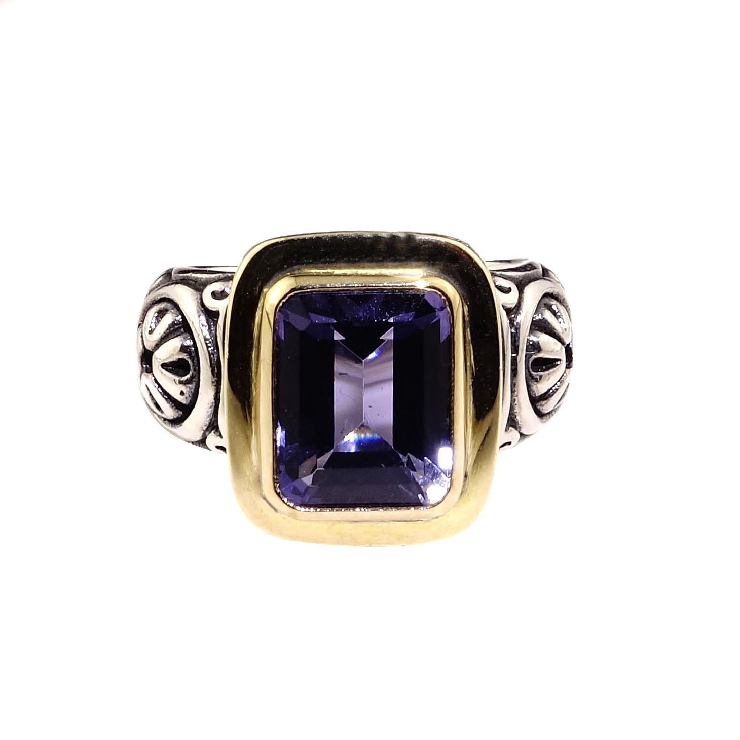 Stunning Sterling Silver ring showcasing an emerald cut blue Iolite bezel set in 18K yellow gold. This is Steven Battelle ring featuring all of his attention to detail and comfort.  The Sterling Silver shank and head are etched and beautifully