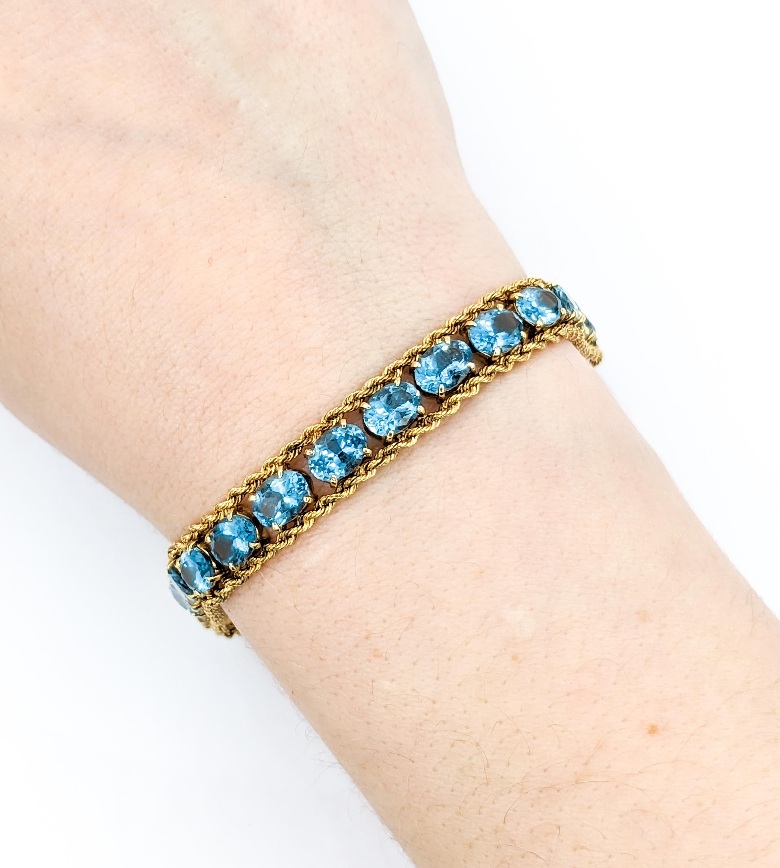 Sparkling Blue Topaz & 14K Gold Chain Bracelet

Immerse yourself in the vibrant elegance of this stunning bracelet, crafted in the warm glow of 14kt yellow gold. Adorned with twenty-four captivating oval-cut blue topaz stones, each measuring 5 x