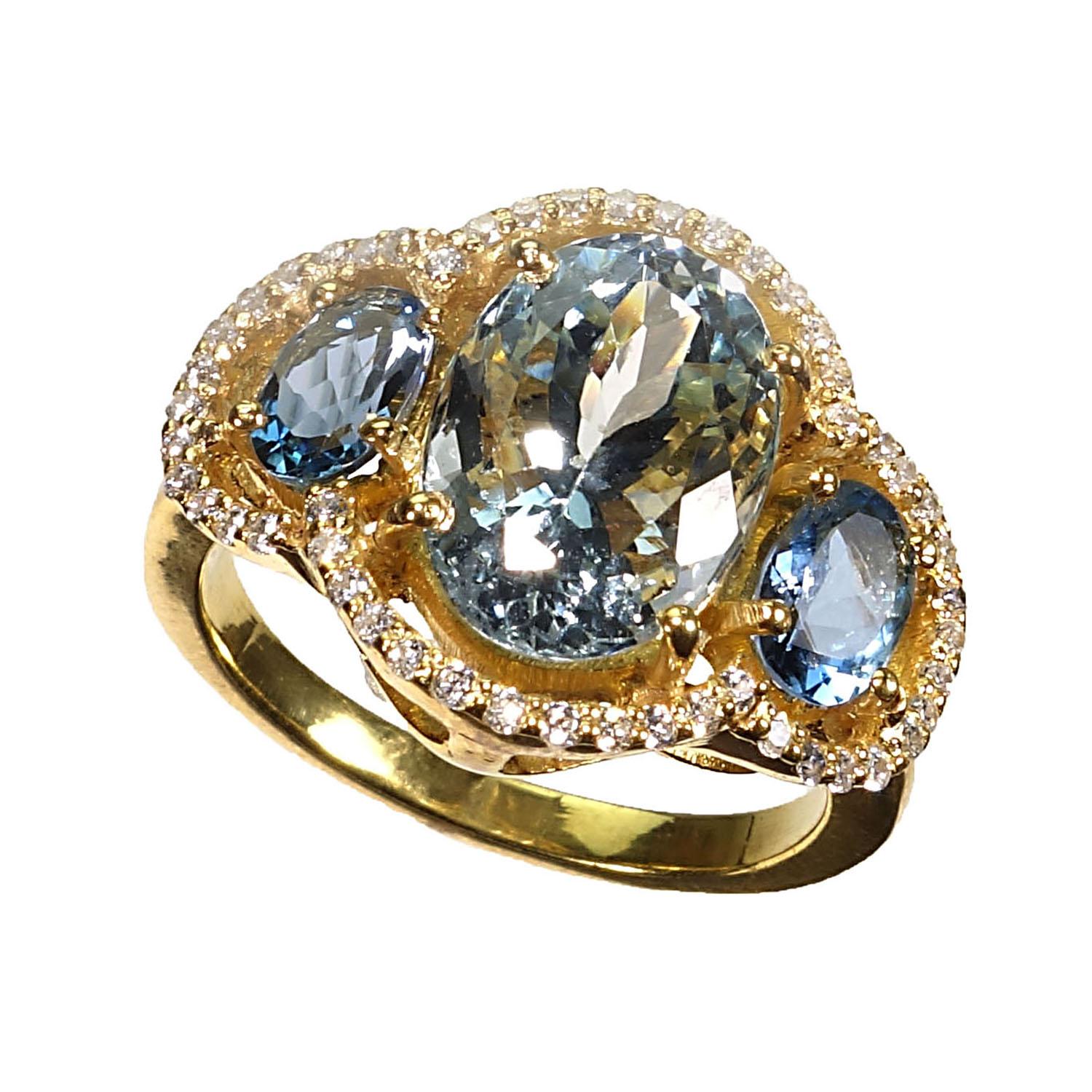 Custom made, glittering ring of oval Aquamarines halo set with Cambodian Zircons in glowing 14K yellow gold rhodium on Sterling Silver. One sparkling oval Aquamarine is flanked by two slightly darker oval Aquamarines. All three are surrounded by