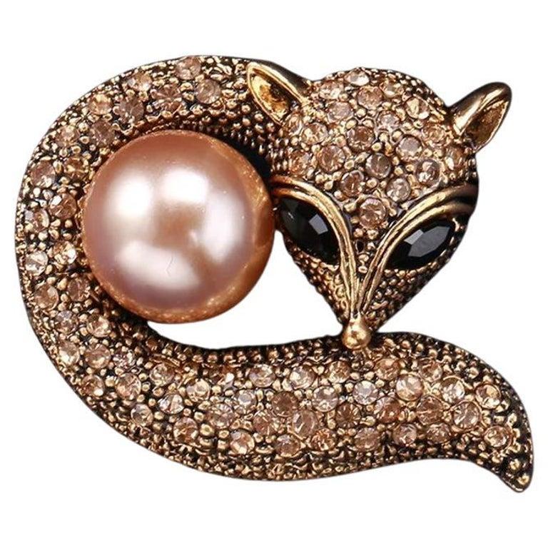 Einfach entzückend! Vintage Golden Crystal Fox mit einer Faux Pearl Brosche Pin. Der Fuchs ist wunderschön mit funkelnden goldenen Kristallen besetzt, die eine Kunstperle umschließen. Gelbgoldfarbene Fassung. Sehr detailliert, mit 3D-Effekt.