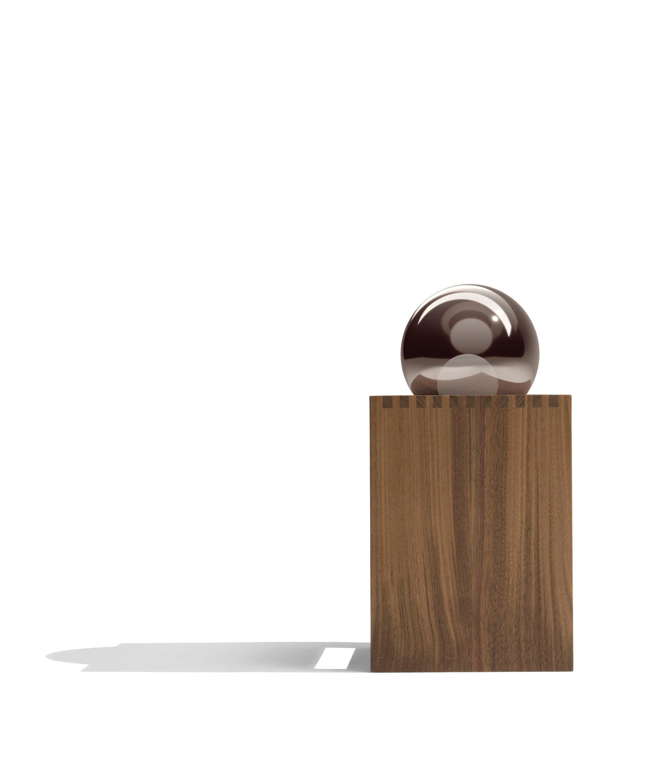 Lampe de table avec structure en noyer Canaletto fin. 11 et fin. 2W, enrichie par le détail du joint en peigne, base en marbre Calacatta et diffuseur formé d'une double sphère : verre réfléchissant couleur bronze, pour accentuer l'éblouissement de