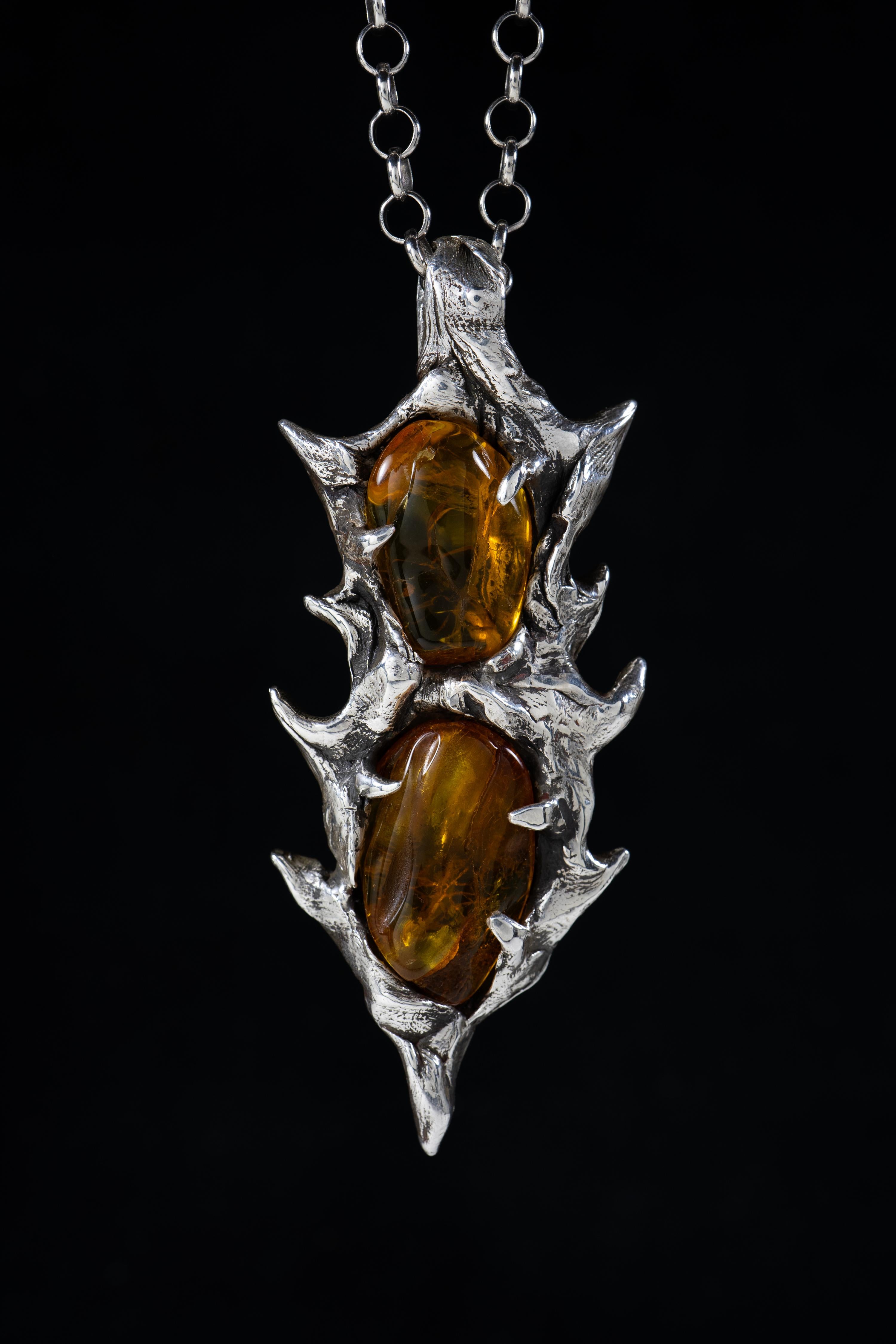 Spear of Immortality is a one-of-a-kind pendant by Ken Fury that is hand-carved and cast in sterling silver with natural Baltic Amber stones from Poland.

Size of piece: 92mm x 37mm

Hand-signed.

A 24-inch sterling silver chain is available as an