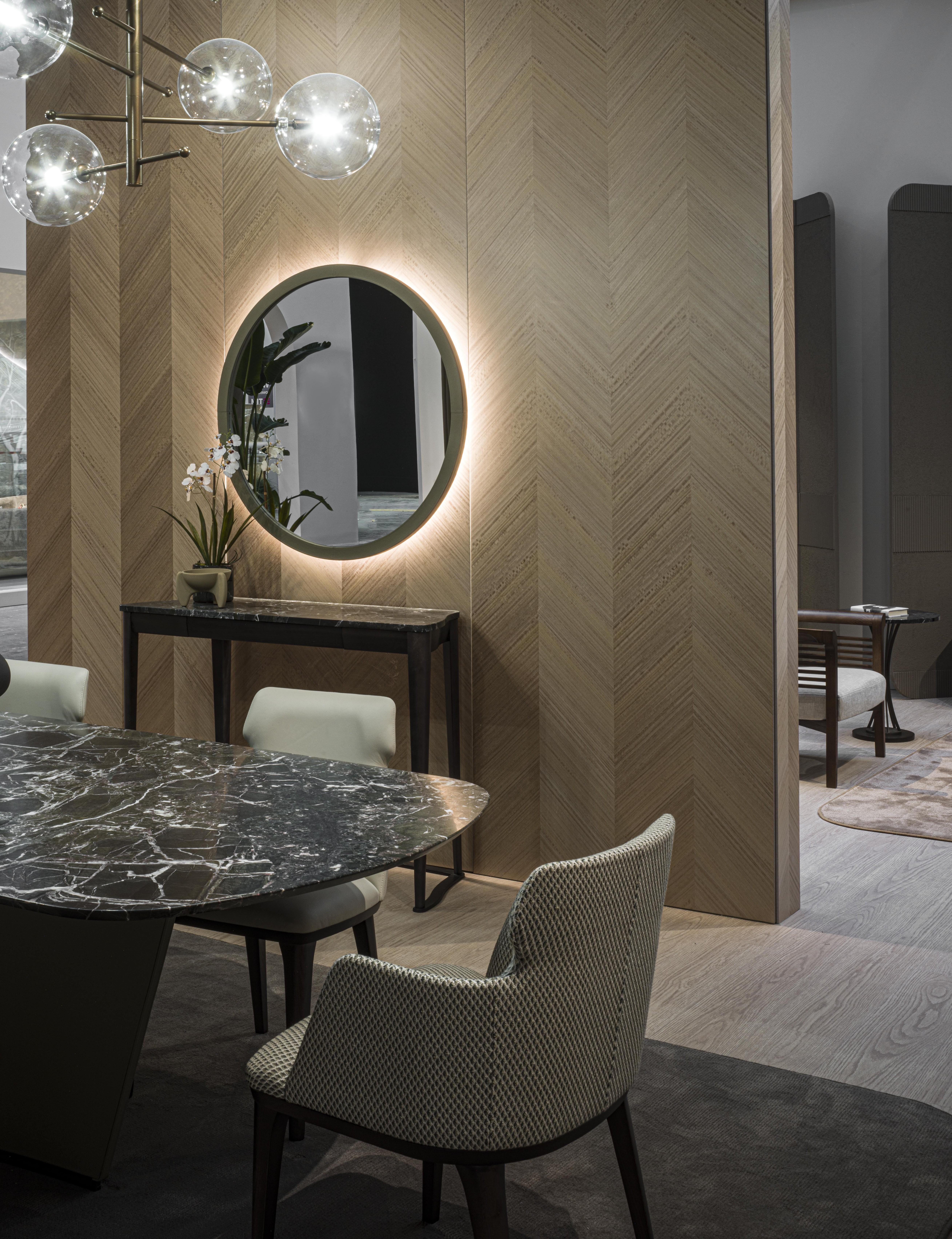 Globe mirror with a simple shape, enhanced by its leather-covered edge with visible stitching. Equipped with backlighting that creates an elegant atmosphere in the room where it is placed. 