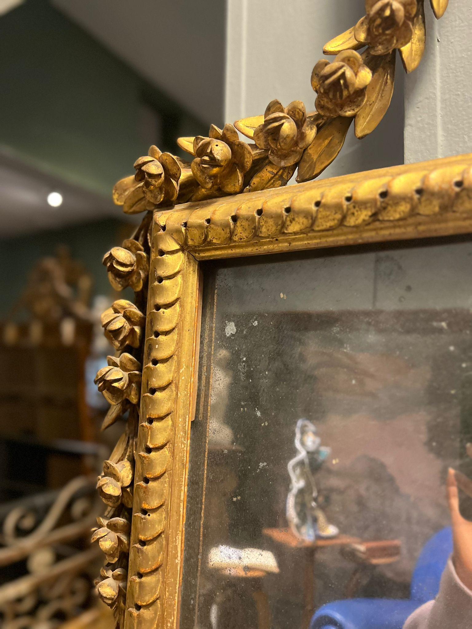 Beautiful Louis XVI mirror in carved and gilded wood.

Extremely refined is the cymatium, which is richly carved in the form of a flower vase from which cords extend laterally. 

Of fine quality are the carvings and gilding. Also nice is the