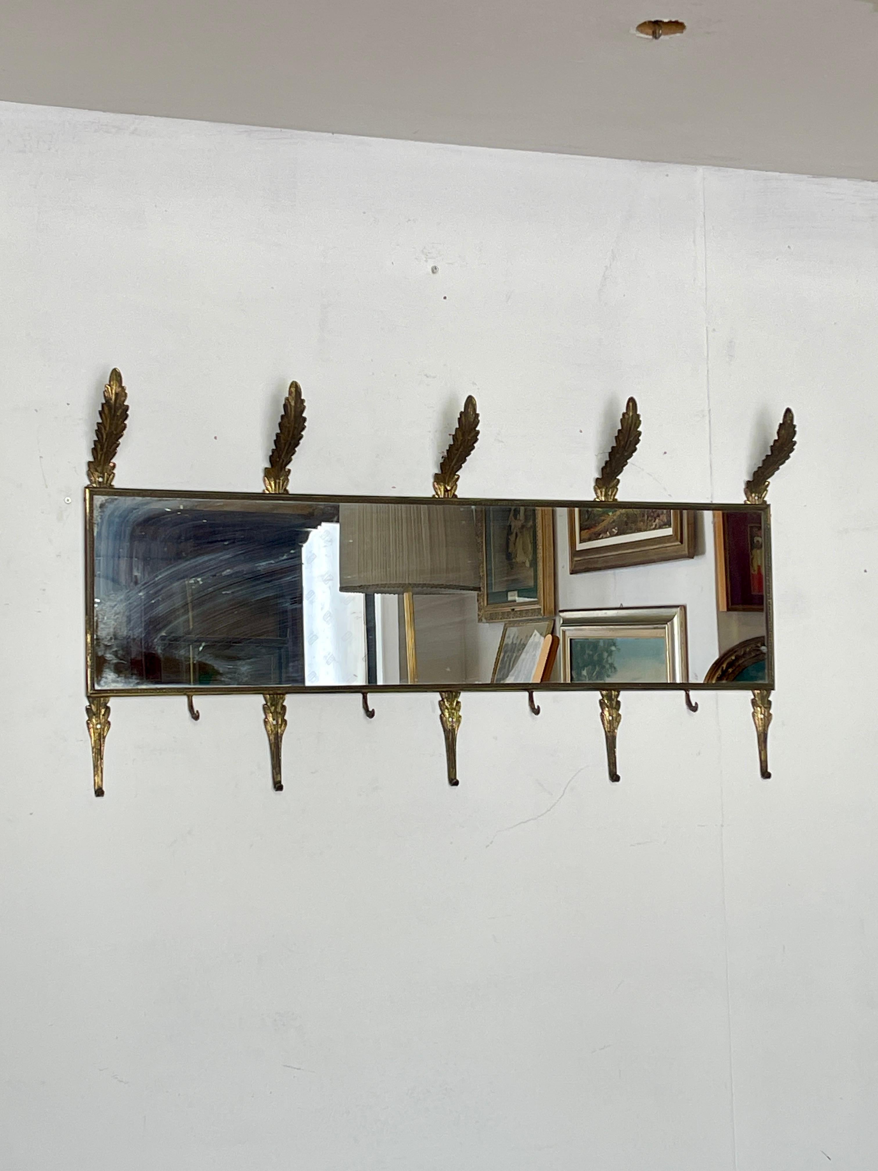Raffinierter Wandspiegel im Vintage-Stil, verziert mit Messingdetails, die mit Blattmotiven gearbeitet sind. Ausgestattet mit 6 unteren Garderobenhaken und 5 eleganten oberen Haken, ist dieser Spiegel ideal für Flure, Korridore oder Retro-Räume. Der
