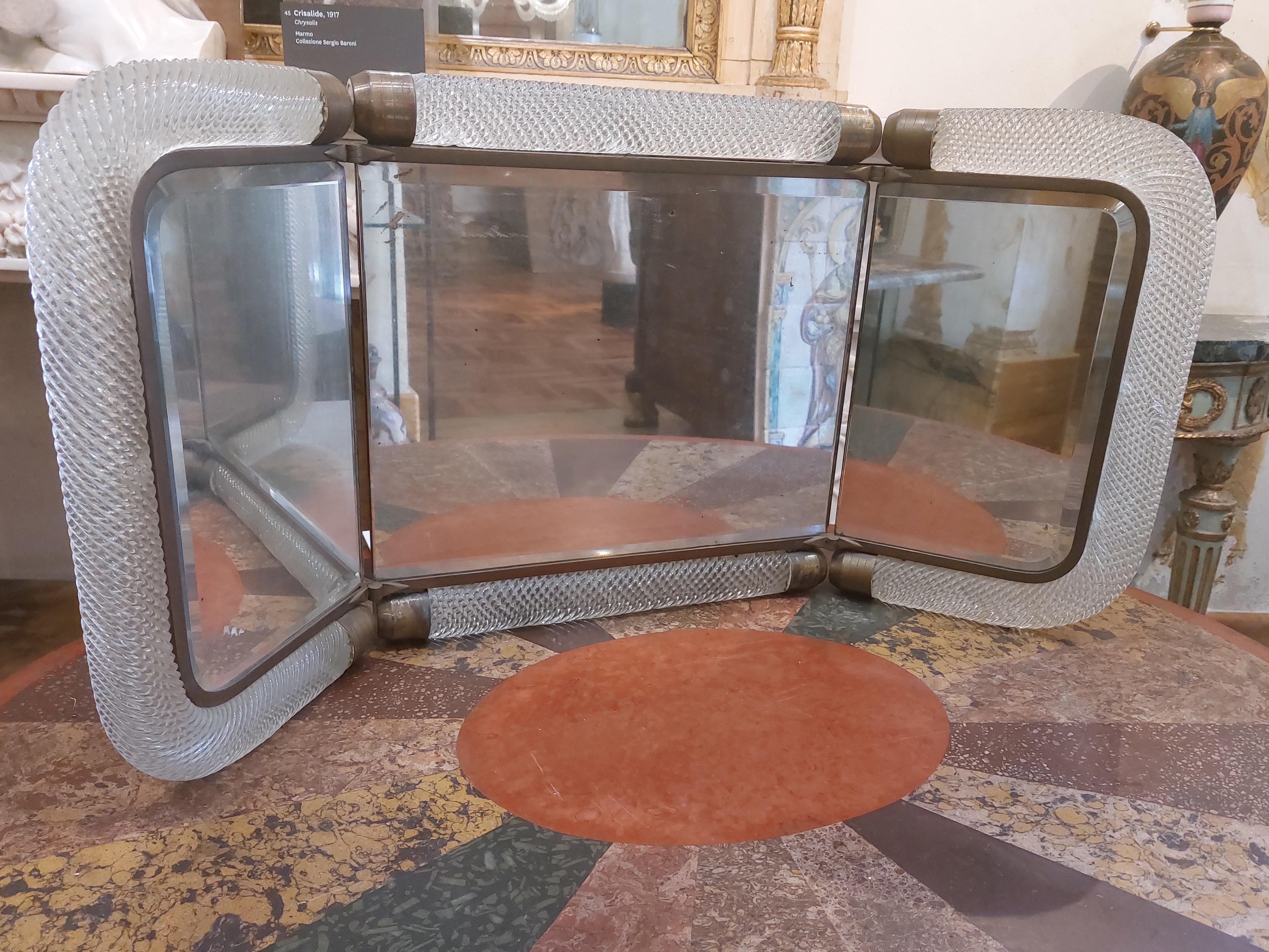 Espejo tocador plegable con tres puertas en cristal de Murano transparente trabajado en torchon, Venini, estilo Decó, Venecia años 30.
Una característica especial es la percha trasera que proporciona más apoyo cuando se coloca sobre una