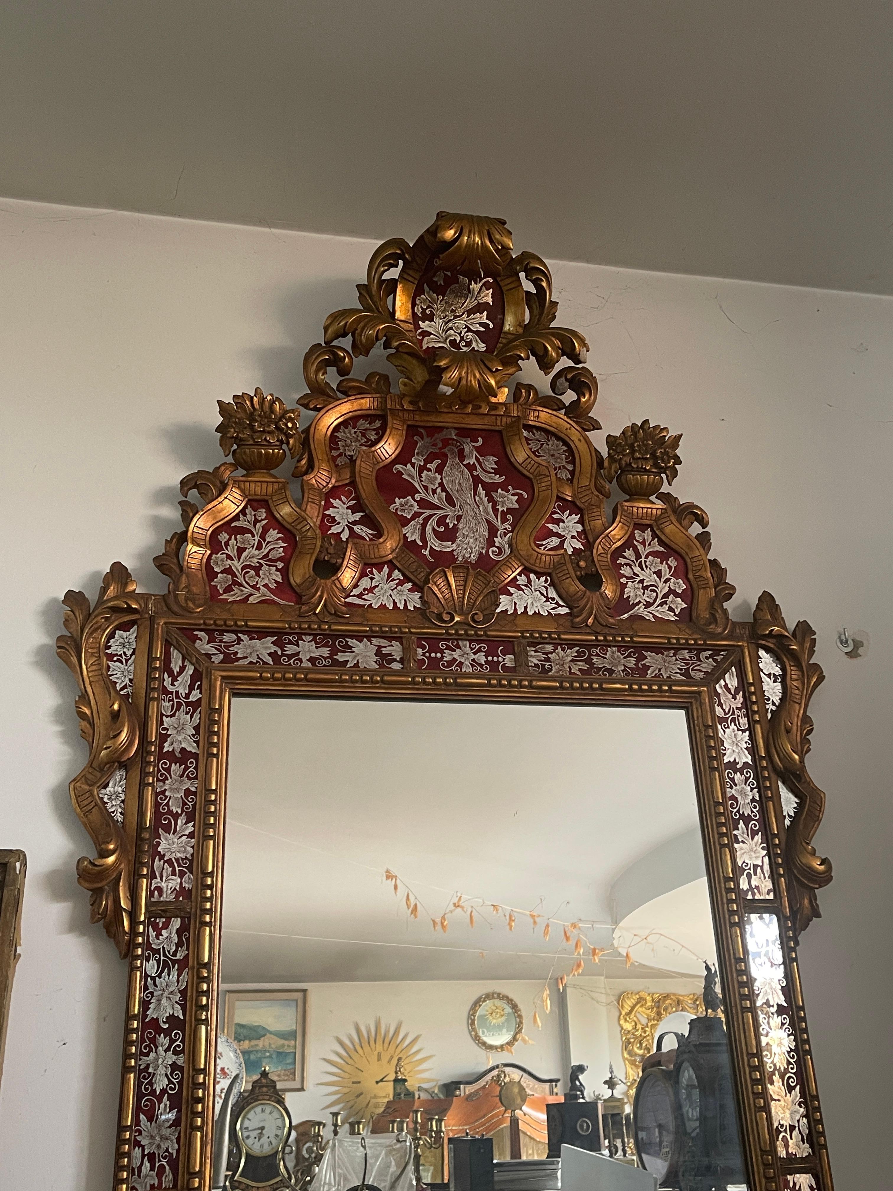 El espejo antiguo de estilo barroco es una verdadera obra maestra de elegancia y refinamiento. El marco dorado, decorado con detalles florales y finos acabados, enmarca el reflejo con un toque de lujo atemporal. El sofisticado diseño y el contraste