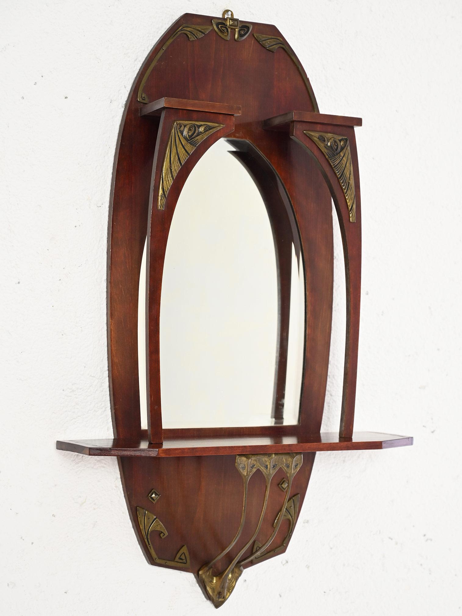 Elégant miroir scandinave vintage.

Un meuble au goût classique et raffiné qui se distingue par la structure particulière de son cadre qui comporte une petite étagère et plusieurs décorations en laiton de style art nouveau.
Grâce à sa petite taille