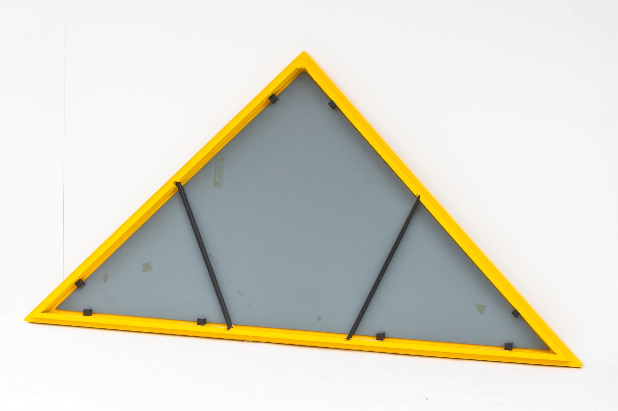 Spiegel mit gelbem, dreieckigem Rahmen von Anna Castelli Ferrieri, Made in Italy, 1980er Jahre. 
Der Spiegel wurde 1982 von Kartell hergestellt und von Anna Castelli Ferrieri entworfen. Der gelbe dreieckige Spiegel ist Teil der Kollektion Italian