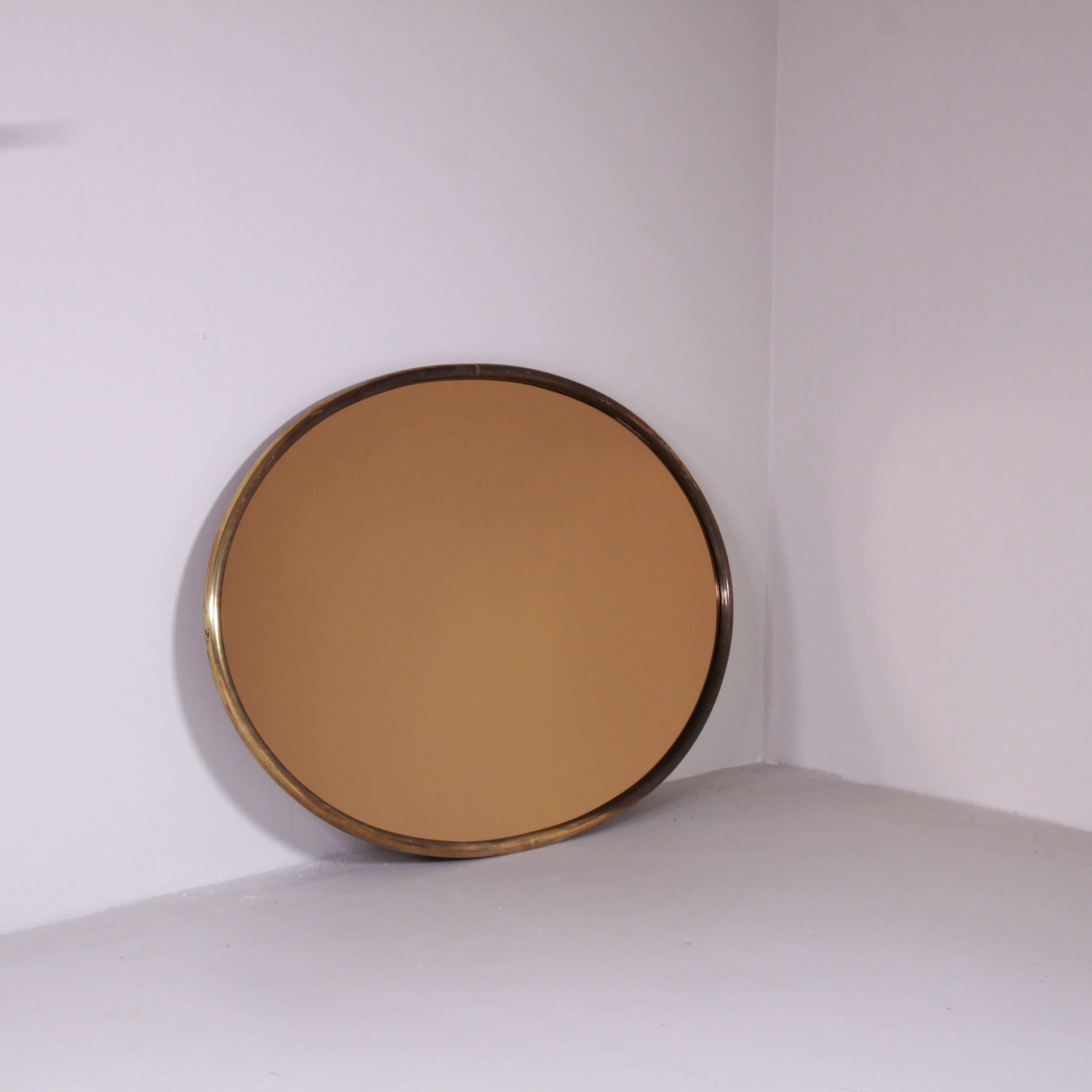 Elegant 1970s mirror with smoked glass, featuring a refined brass frame that enhances its sophisticated and timeless design. The contrast between the smoked glass and the golden brass finish lends a touch of class and sophistication, perfect for