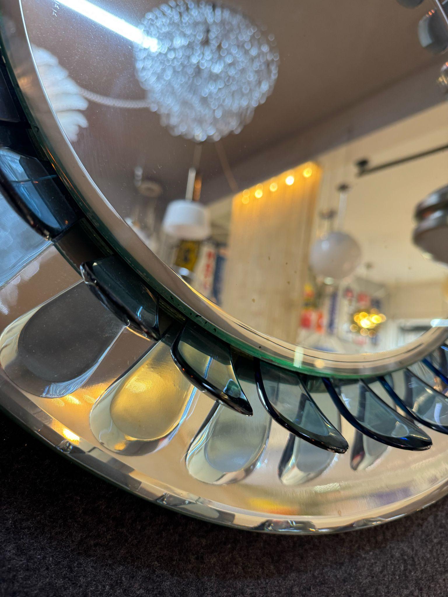 An icon of Italian design by Max Ingrand for Fontana Arte, this extraordinary 1960s circular mirror is a perfect balance of sculptural elegance and industrial sophistication. The curved glass frame, composed of transparent, drop-cut elements