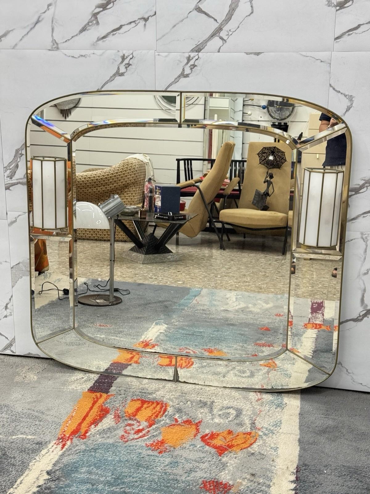 Miroir mural avec applique - années 1970, style Hollywood Regency

Fascinant miroir mural de style Hollywood Regency des années 1970, agrémenté d'une paire d'appliques murales intégrées sur les côtés. Le cadre en métal doré et les inserts en miroir