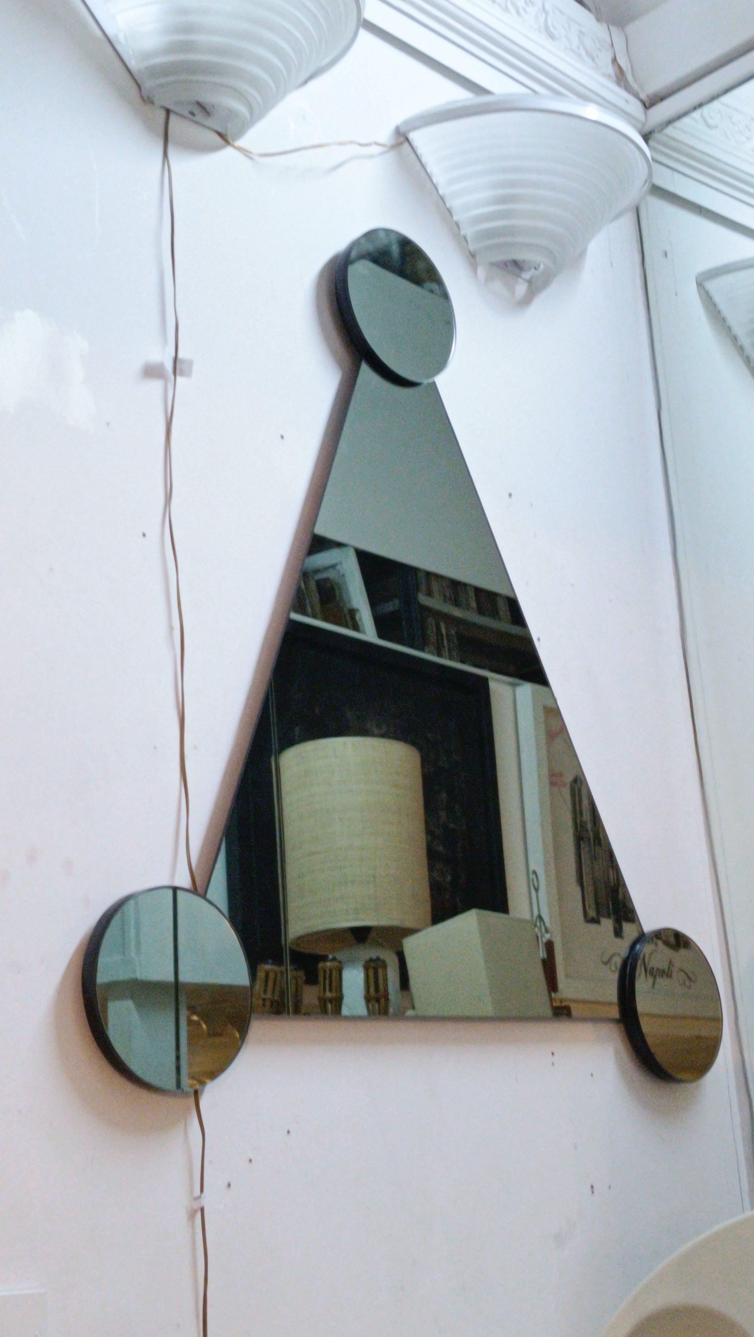 Large wall mirror with main triangular shape and three smaller circular mirrors. The design is clearly modern and artistic, with a combination of shapes and reflections creating an interesting visual effect, serving as both a decorative and