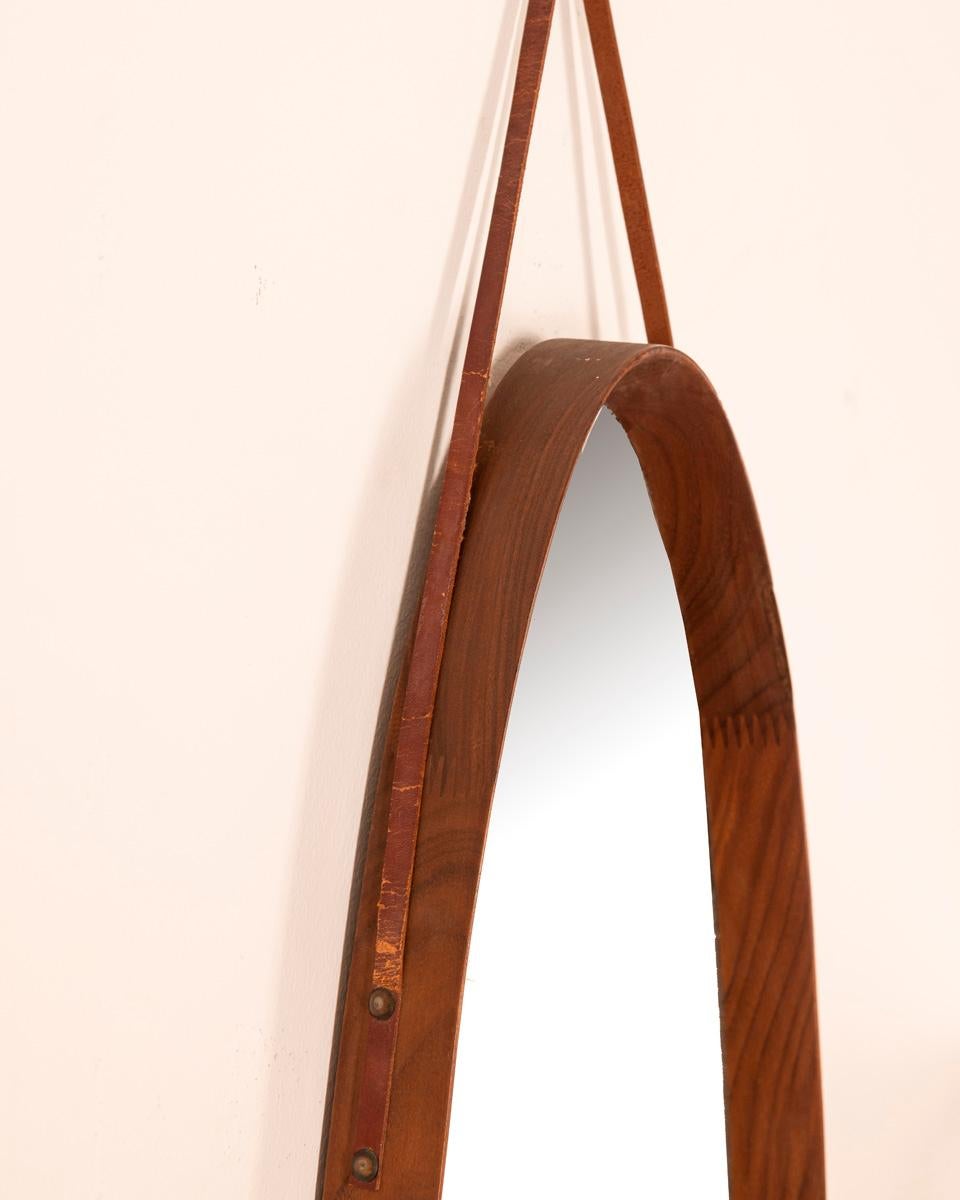 Wall mirror with teak wood frame and leather cord, Italian design, 1960s.

CONDITION: In good condition, may show signs of wear given by time.

DIMENSIONS: Height 120 cm; Width 31 cm; Length 4 cm

MATERIAL: Wood and glass

YEAR OF PRODUCTION: Anni 60