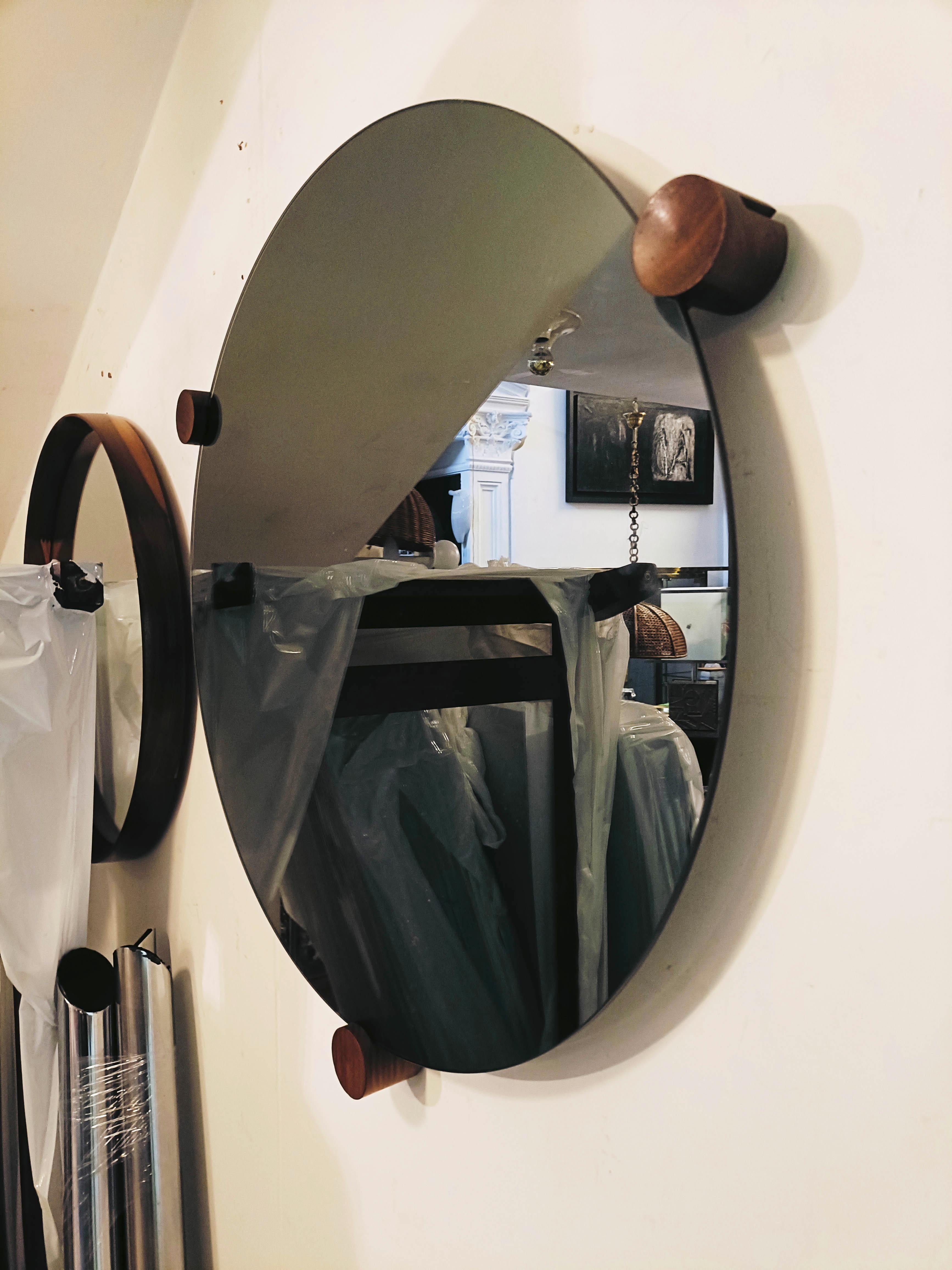 Elegante espejo circular de los años 70, con marco de madera oscura y tres pomos de madera que aportan un toque de calidez y originalidad. Este espejo es una auténtica pieza de diseño de los años 70, que capta el espíritu de una época caracterizada