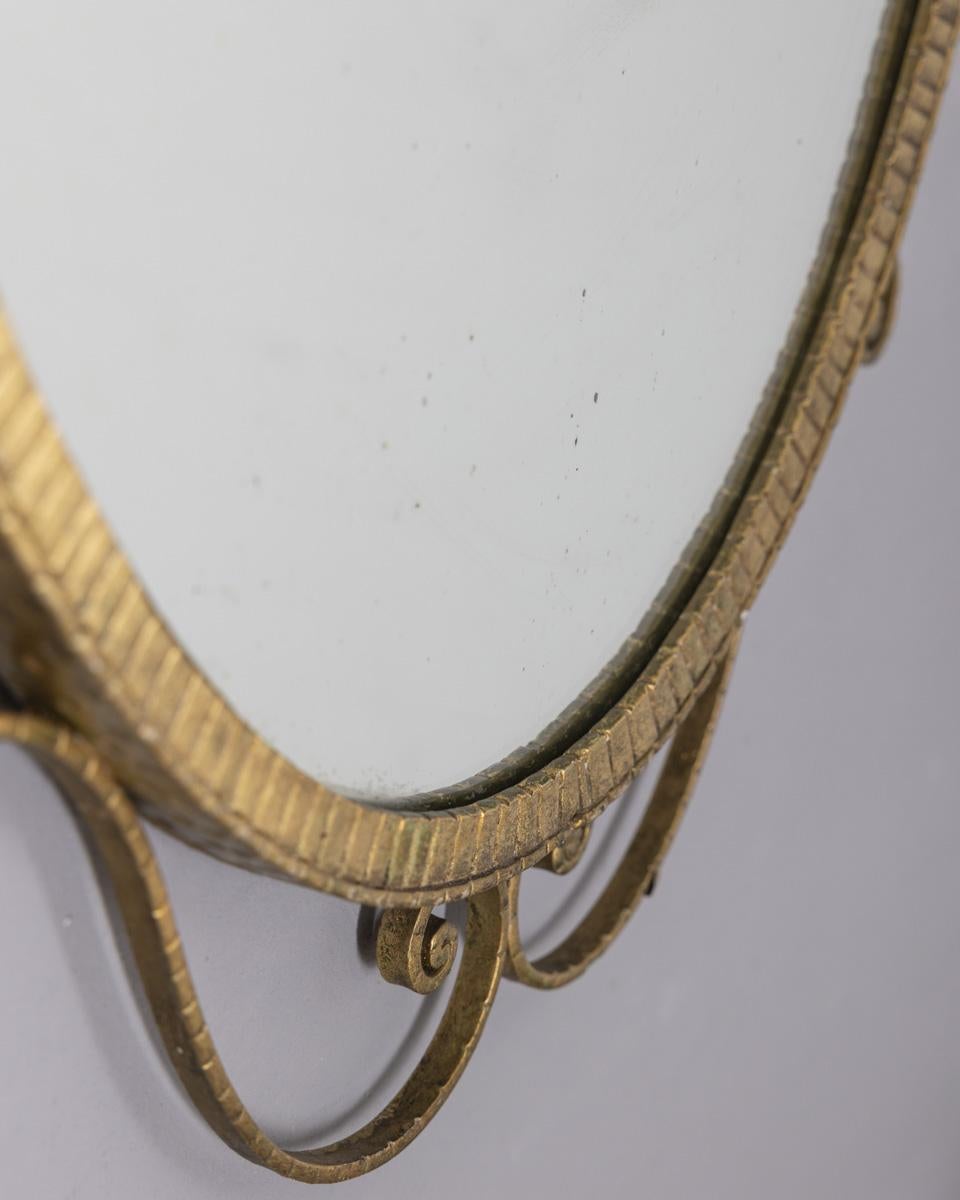 Specchio da parete con cornice in metallo battuto oro, disegnato da Pier Luigi Colli, anni '50.

CONDIZIONE:
In buone condizioni, con segni di usura dovuti al tempo.

DIMENSIONI:
Altezza 102 cm; Larghezza 63 cm; Profondità 3 cm;

MATERIALI:
Metallo