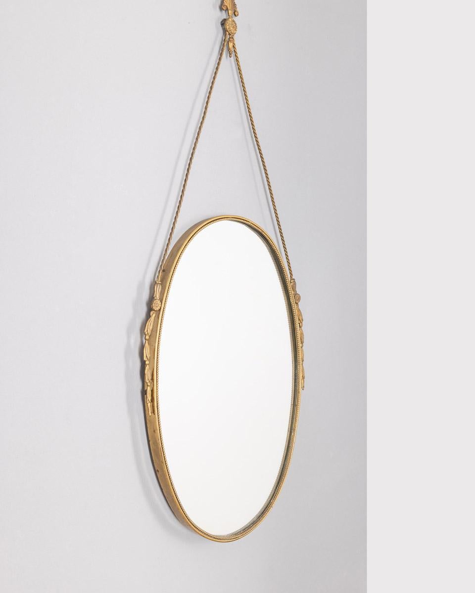 Espejo de pared con marco de latón dorado y decorado y cuerda de latón, diseño italiano, años 50.

CONDICIÓN:
En buen estado, puede mostrar signos de desgaste debido al paso del tiempo

DIMENSIONES: 
Altura 91 cm; anchura 37 cm;  Longitud 3 cm; 