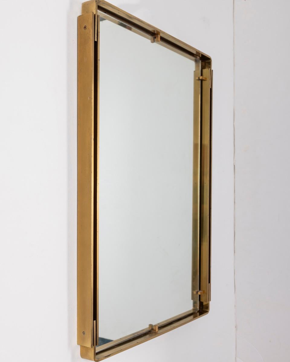 Specchio da parete con cornice in ottone dorato, design Sant'Ambrogio e De Berti, anni 60.

CONDIZIONI: In buone condizioni, presenta segni d'usura dati dal tempo.

DIMENSIONI: Altezza 77 cm; Larghezza 54 cm; Lunghezza 4 cm

MATERIALI: Ottone e