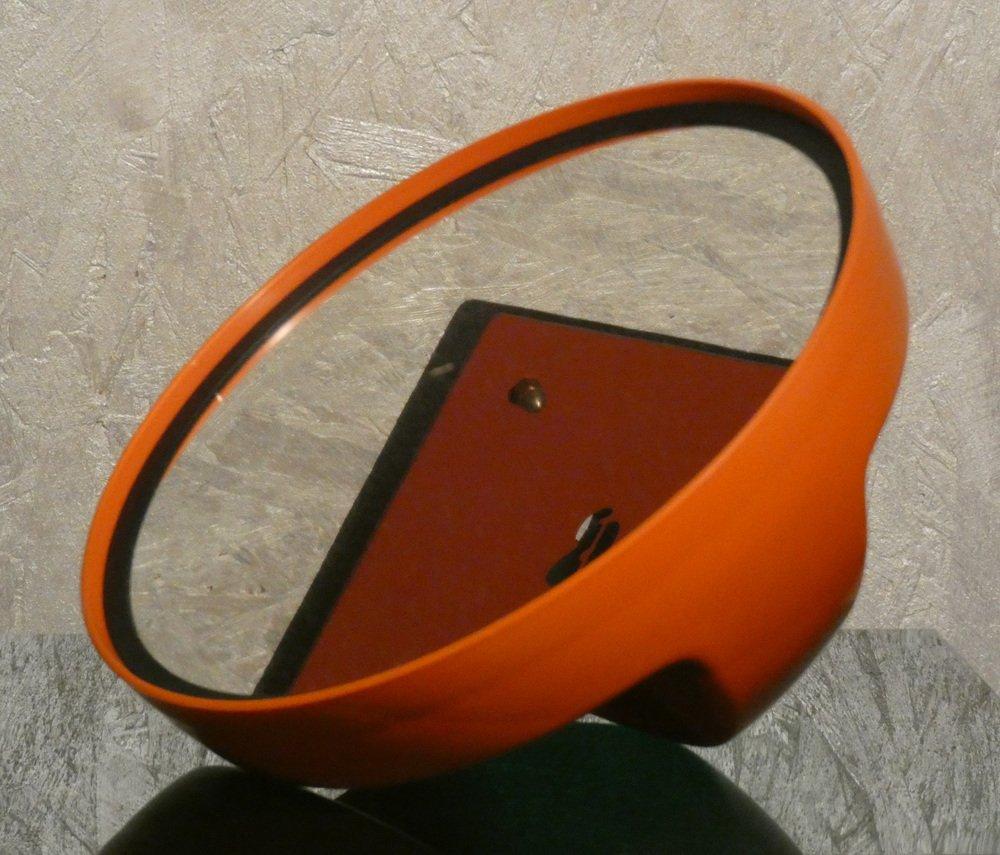 Specchio in plastica Arancione prodotto negli anni 70. Era molto in voga all'epoca questo tipo di specchio, utilizzato anche nei saloni di bellezza, poichè creato per essere appoggiato sul tavolo con l'impugnatura rivolta verso l'alto per