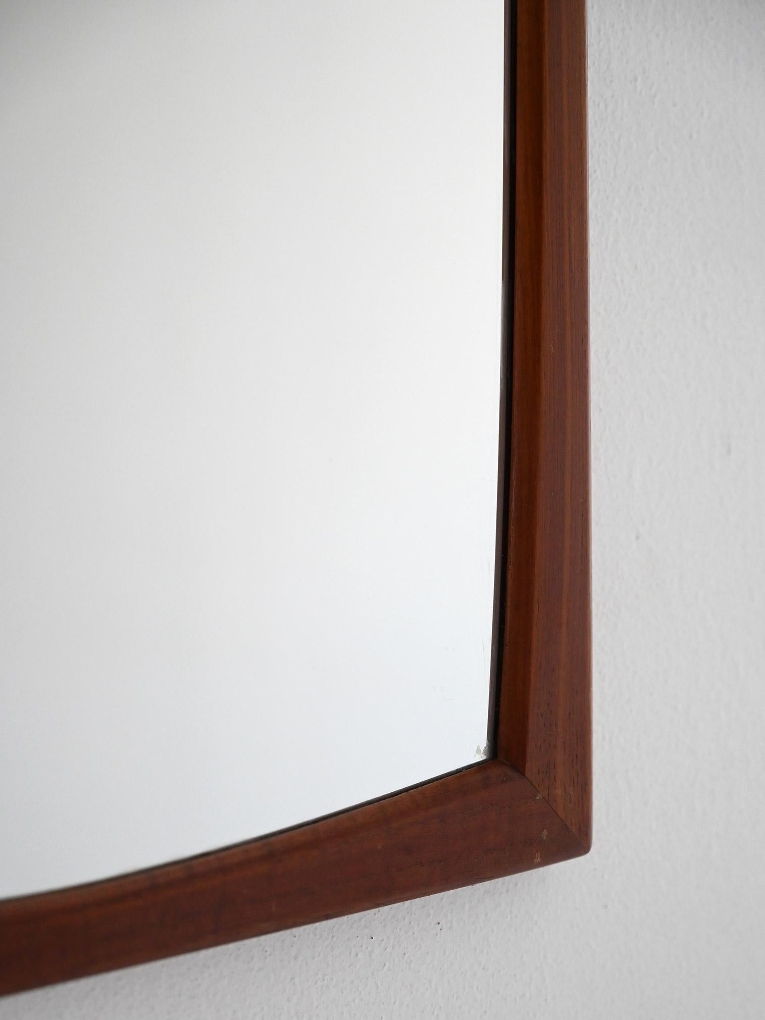 Vintage mirror with convex teak frame designed by Aksel Kjersgaard and original mark on the back.

Wall mirror designed by Aksel Kjersgaard for Odder, made in Denmark in the late 1950s and early 1960s. Solid teak frame with a rounded profile and