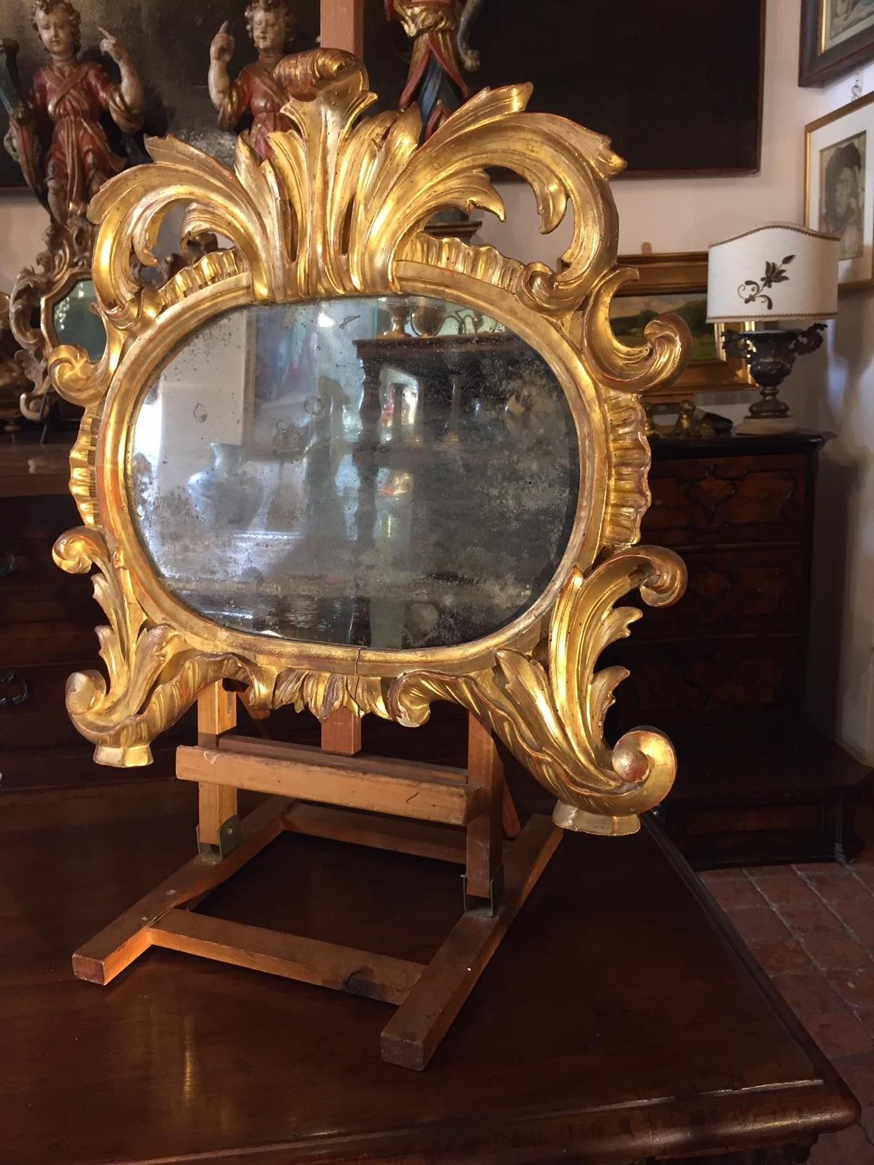 Specchiera Dorata 1750 circa in Legno di cirmolo Intagliato a volute e piedi a ricciolo, con lo specchio al mercurio d'epoca. Diese kleinen italienischen Exemplare wurden ursprünglich als Cartagloria, als von Hand eingearbeitete und verschnörkelte