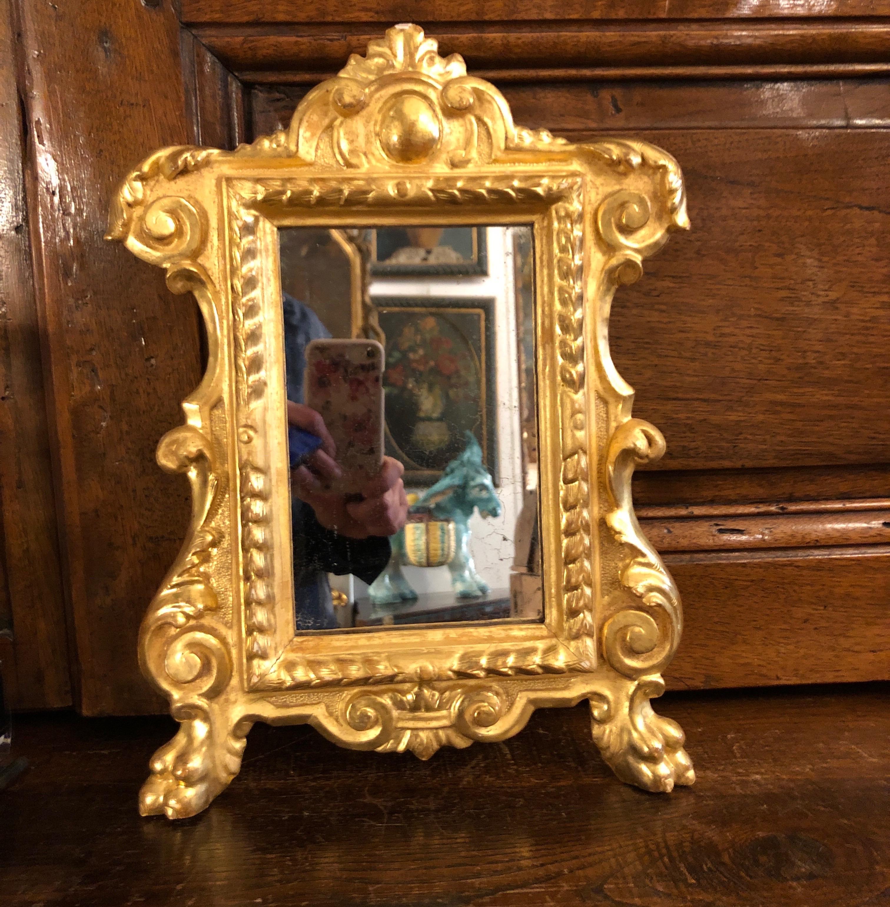 Dall'Italia, un piccolo specchio con cornice intagliata e dorata in foglia dell'inizio 1800.  Questa piccola cornice è un arredo d'altare, un tipoco arredo liturgico italiano cosiddetto cartagloria o cantagloria.
Di forma sagomata, con un ricco