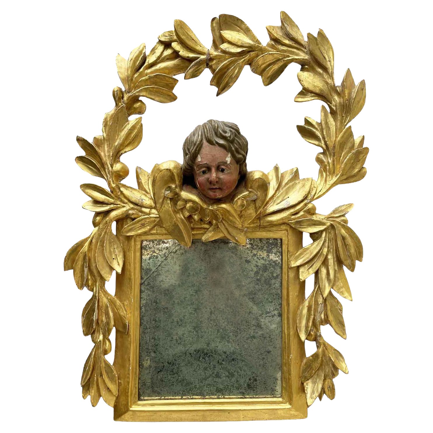 Miroir italien doré avec putto de style baroque mais datant du début des années 1800. Le cadre carré est surmonté de la tête d'un putto ailé encadré par une riche guirlande de feuilles de laurier qui descendent également le long des côtés du cadre. 